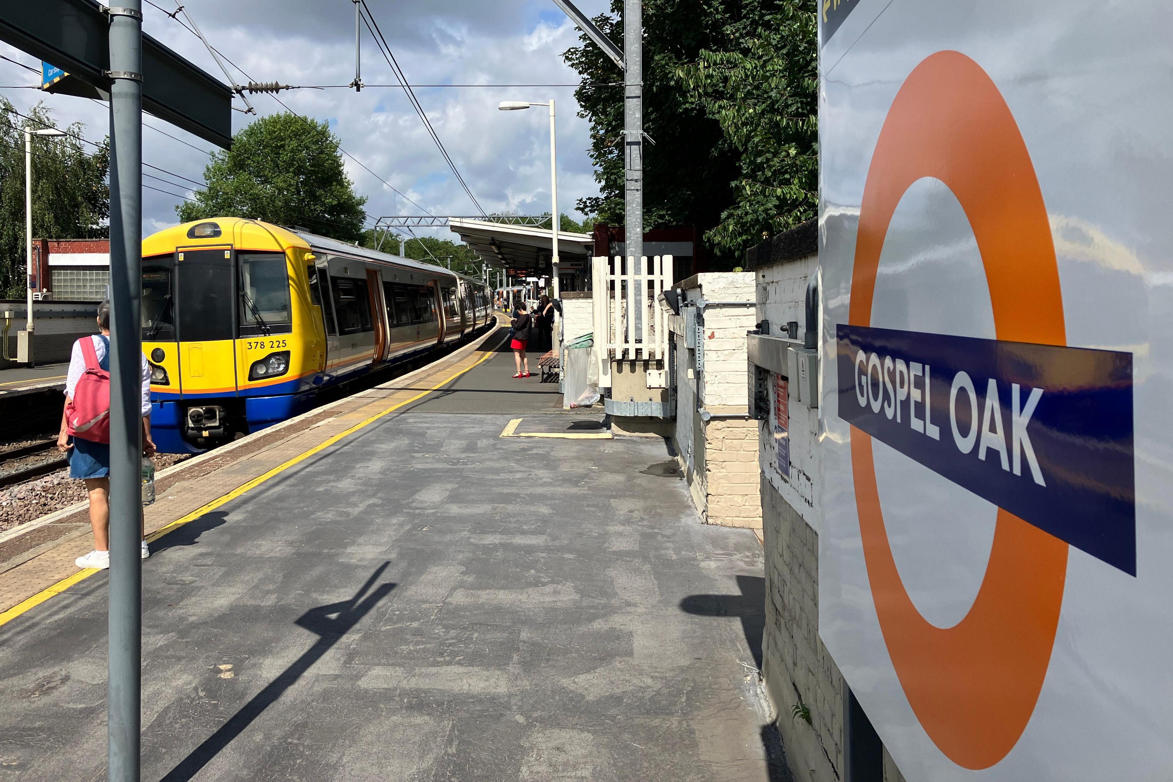 View from Gospel Oak station shows passengers awaiting an incoming yellow train (left) and the roundel (right)