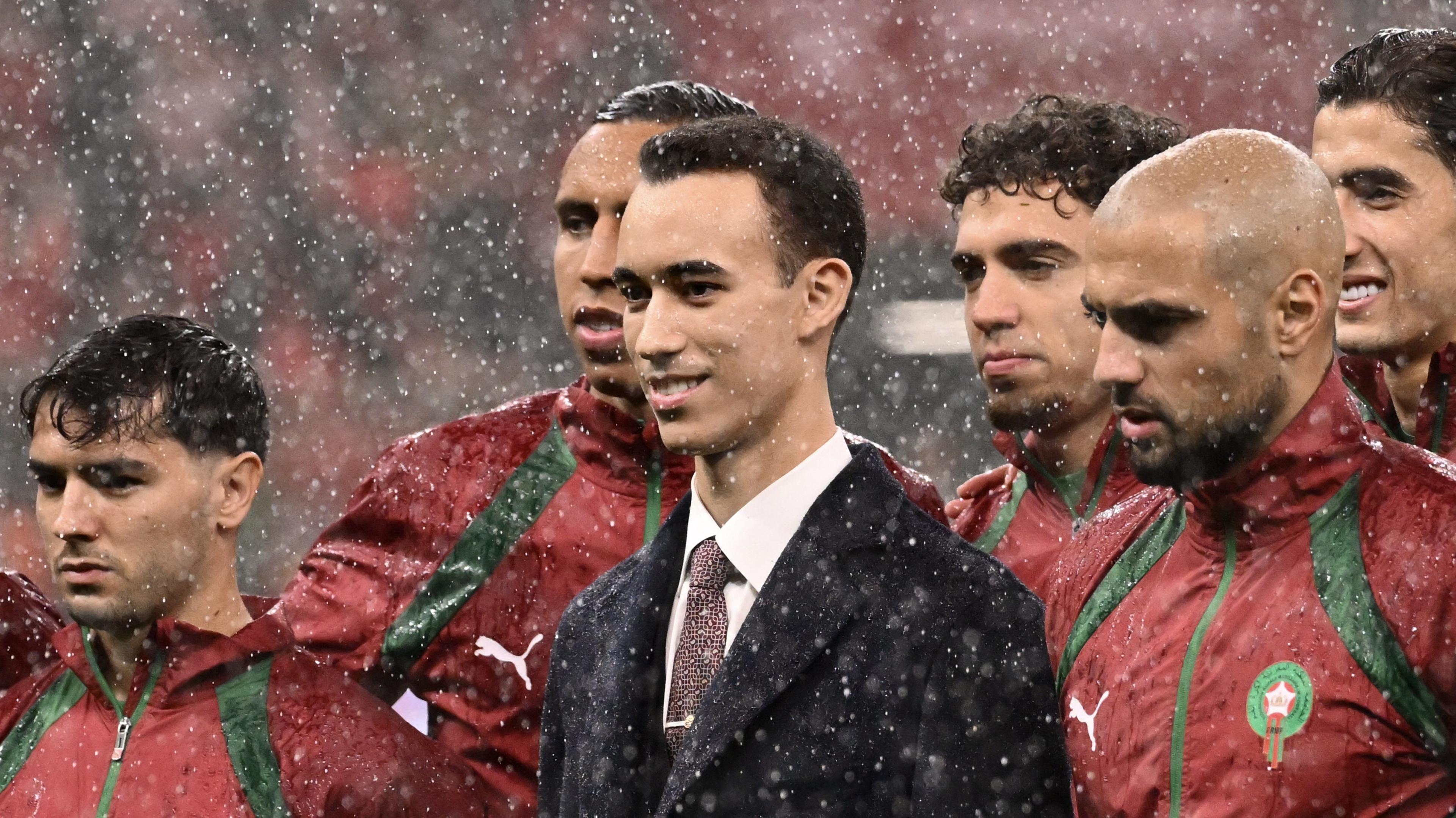 Crown Prince Moulay El Hassan of Morocco stands in the centre of an image surrounded by several Morocco international footballers.