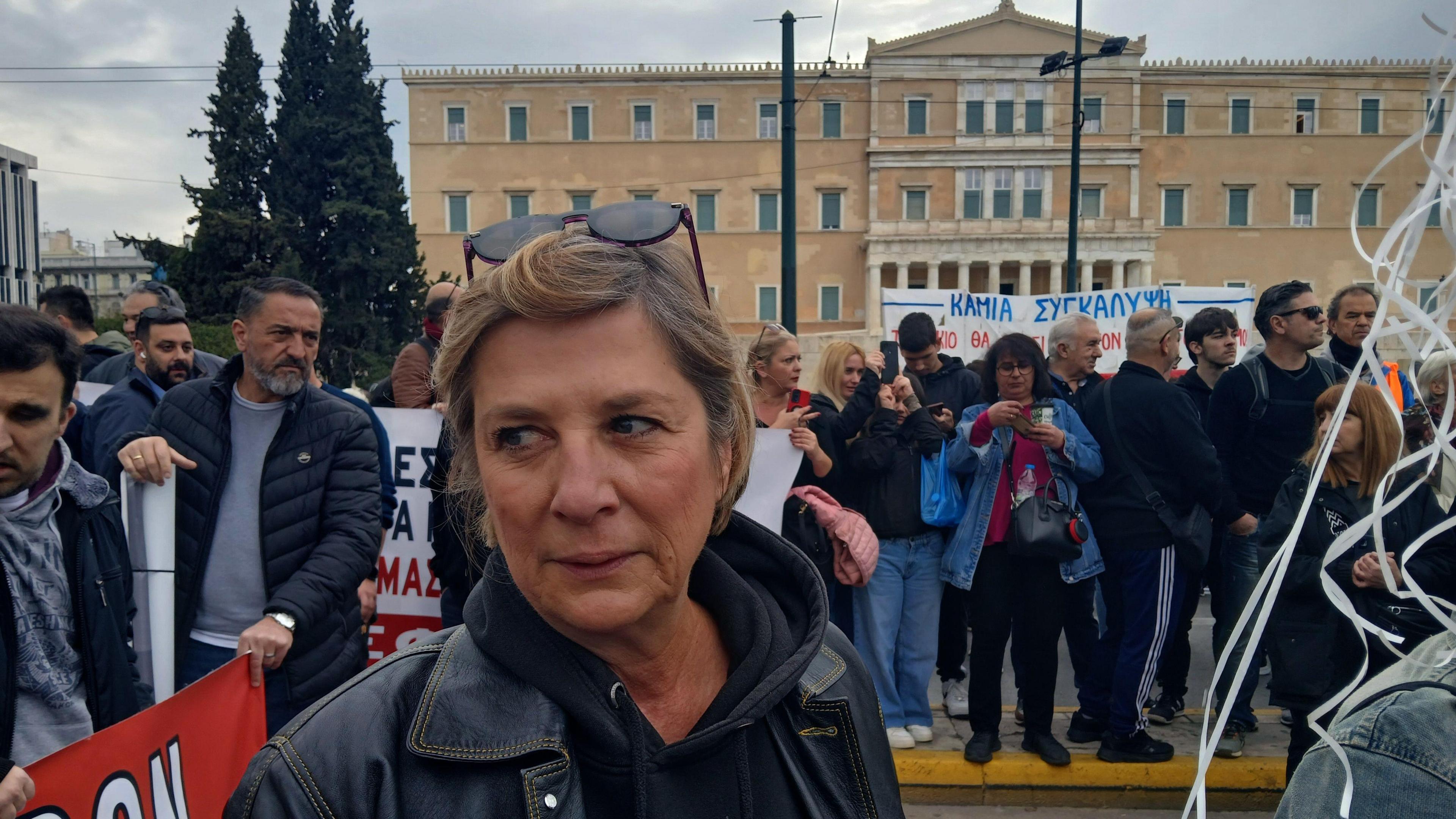 A woman stands among protesters clutching white balloons which are out of the picture