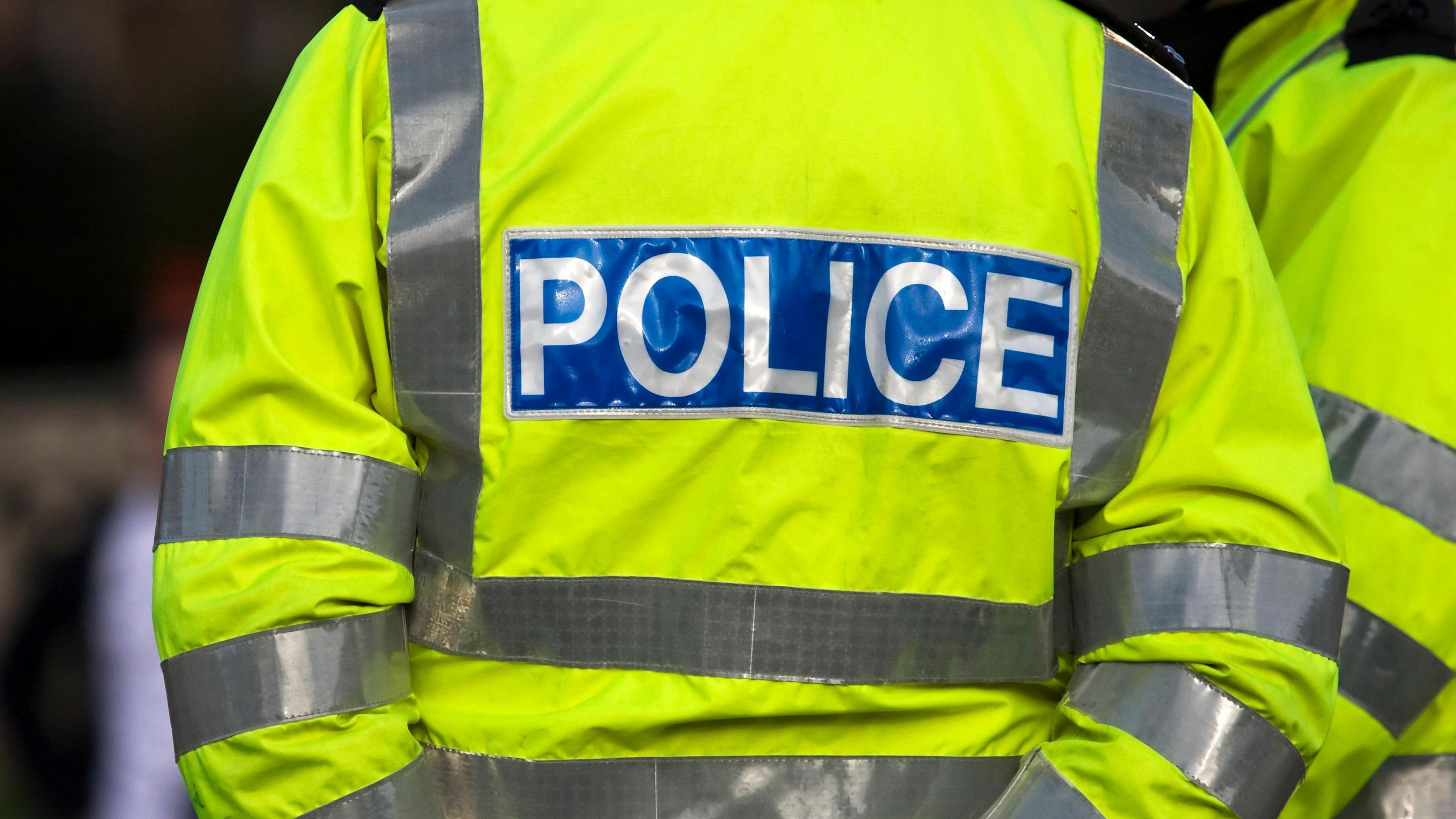 Shot of the back of a police officer's jacket with the word police written across the back