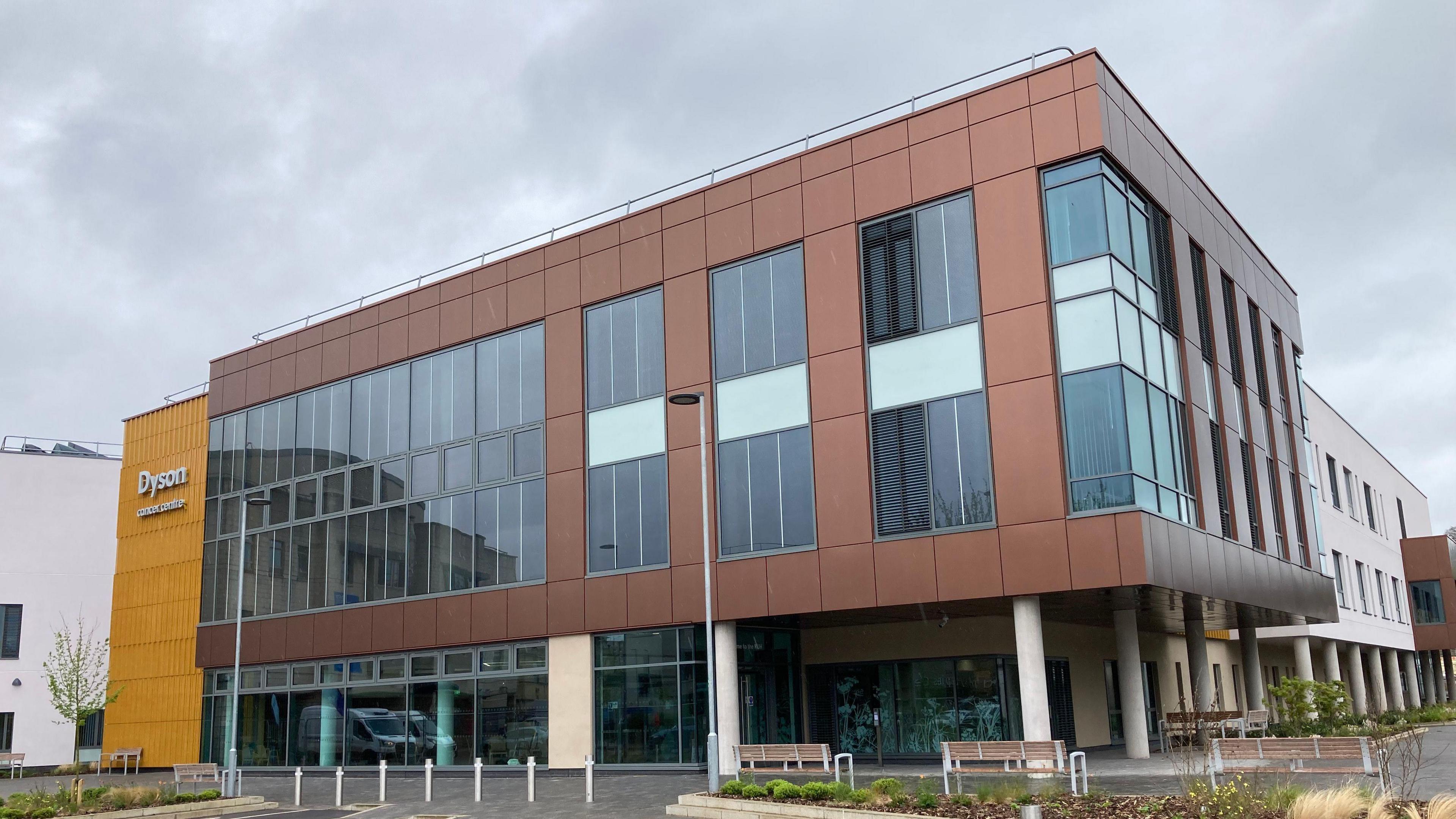 The Dyson Cancer Centre completed from the outside, three levels in a modern design, copper-coloured panels on the walls