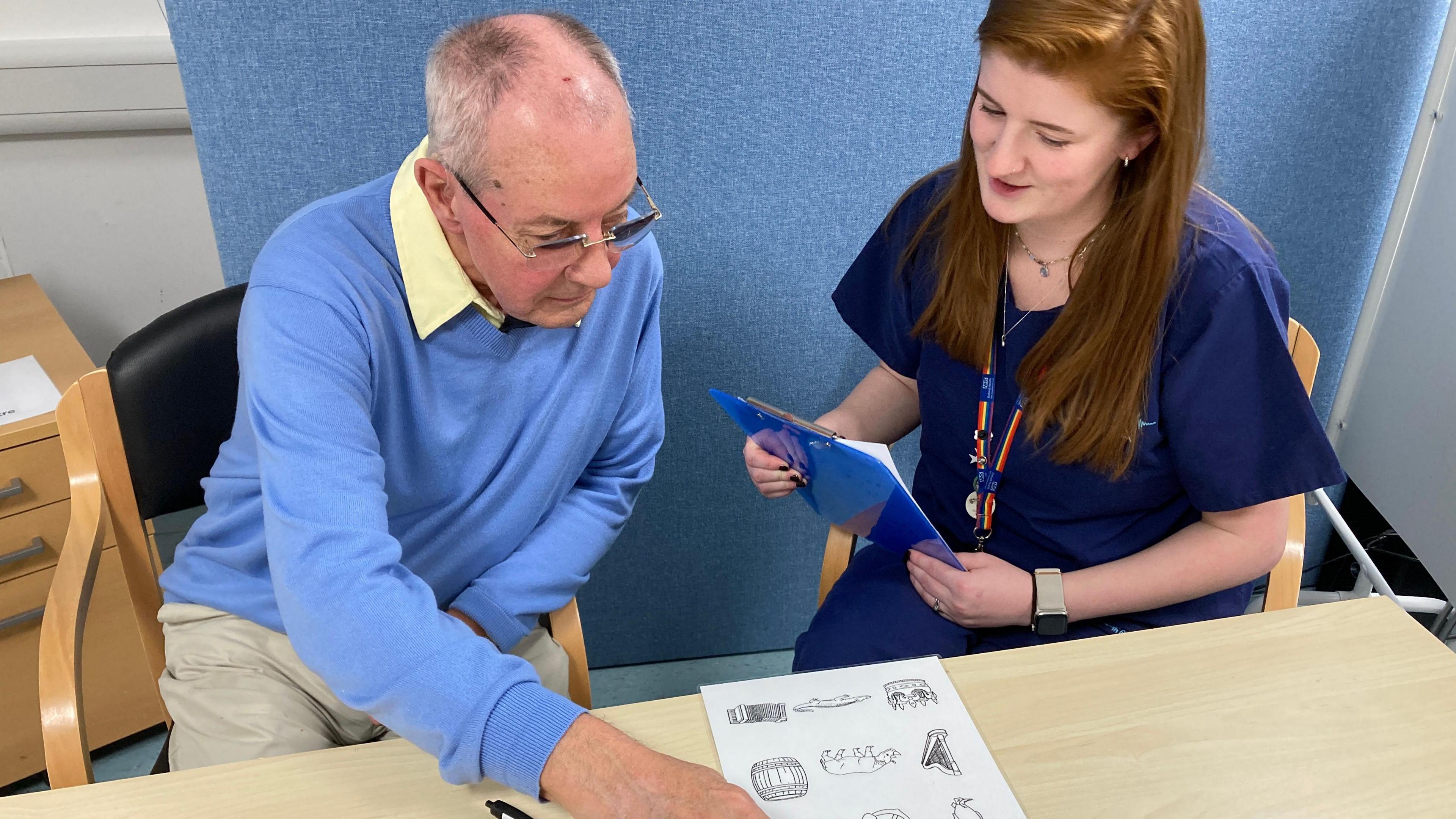 Ron Hill pointing to a memory test sitting next to a clinician