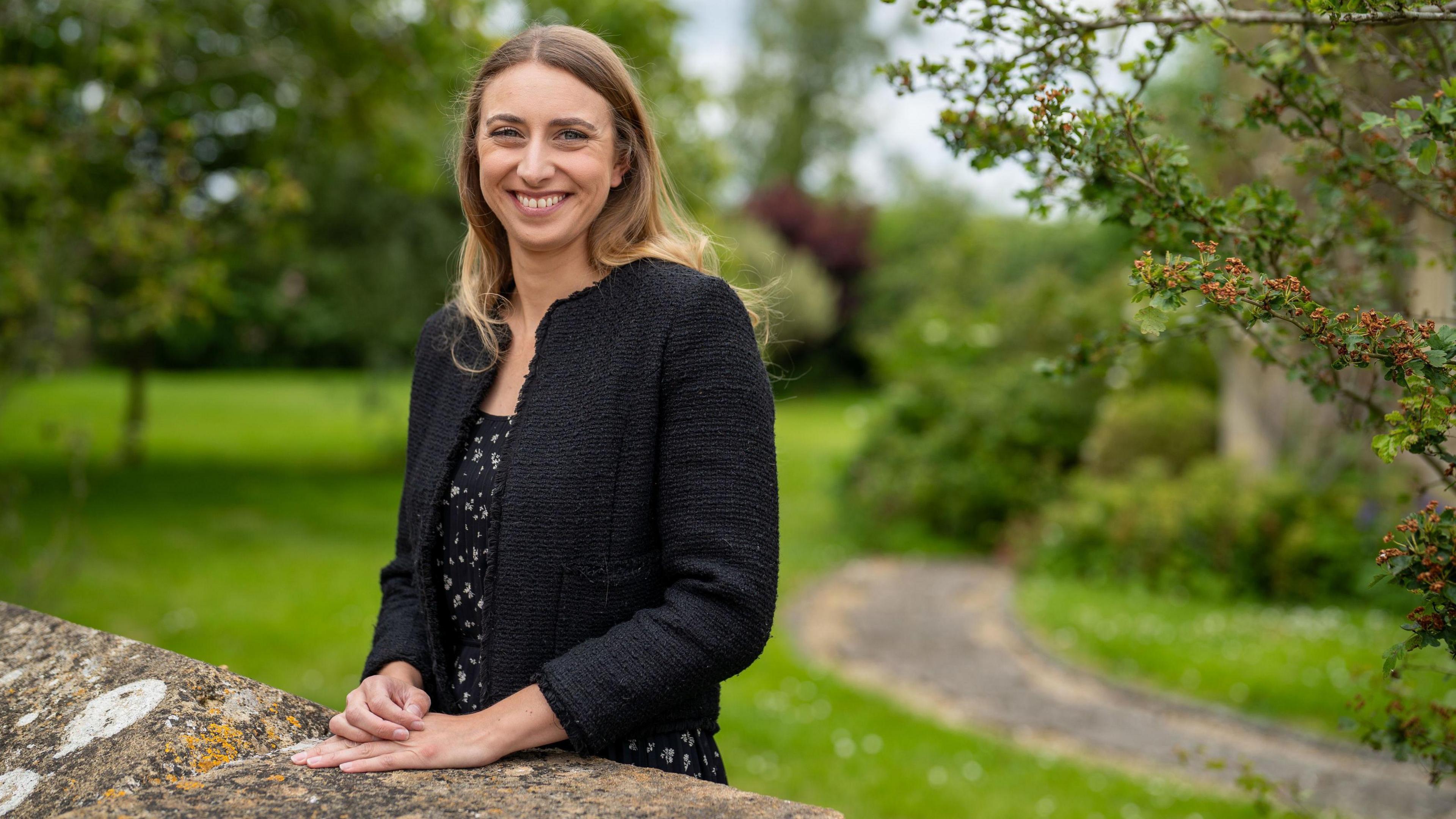 Alicia Hempleman-Adams smiles at the camera while standing in a park in Bristol