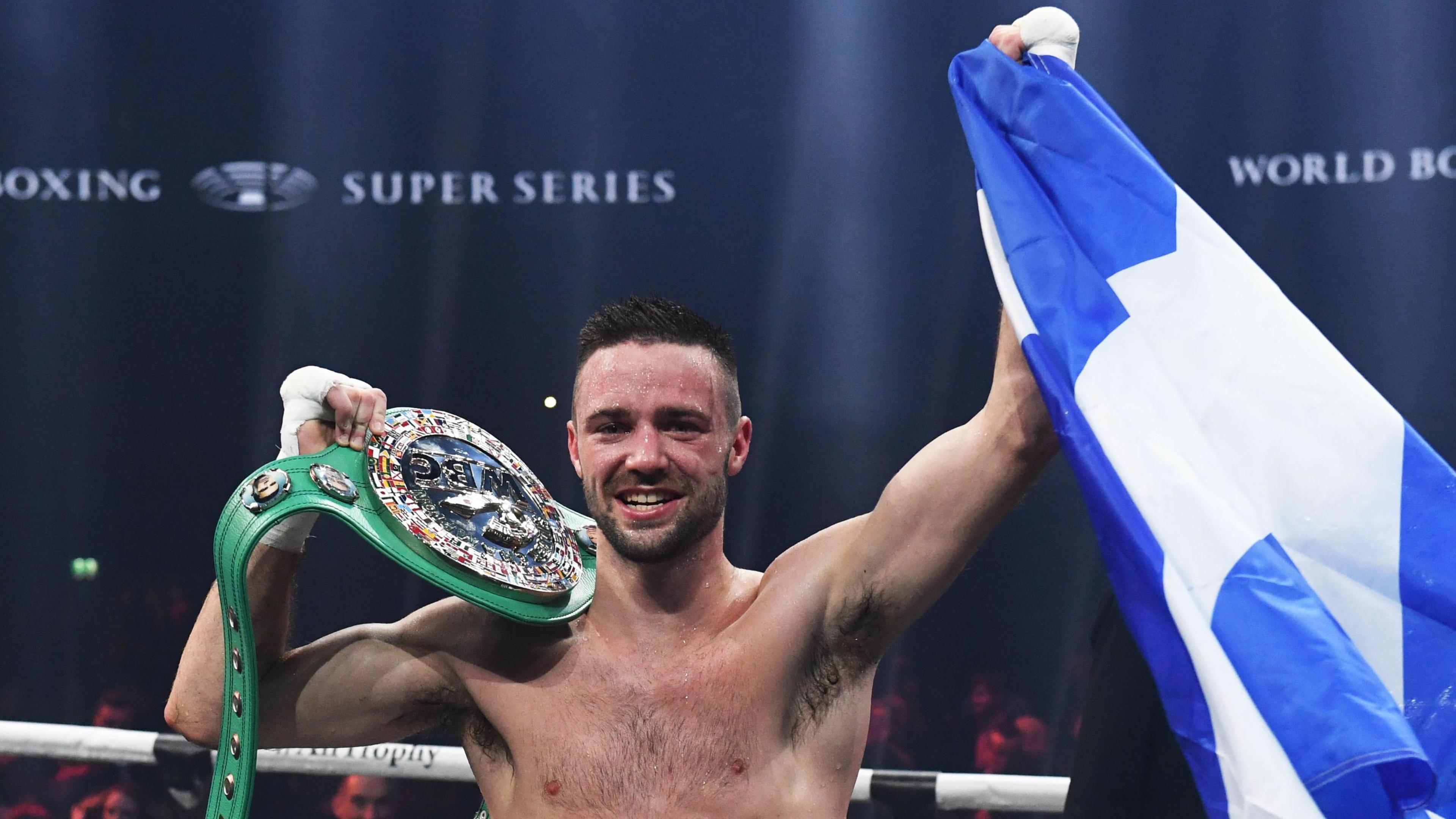 Josh Taylor celebrates winning by holding up the Scottish flag
