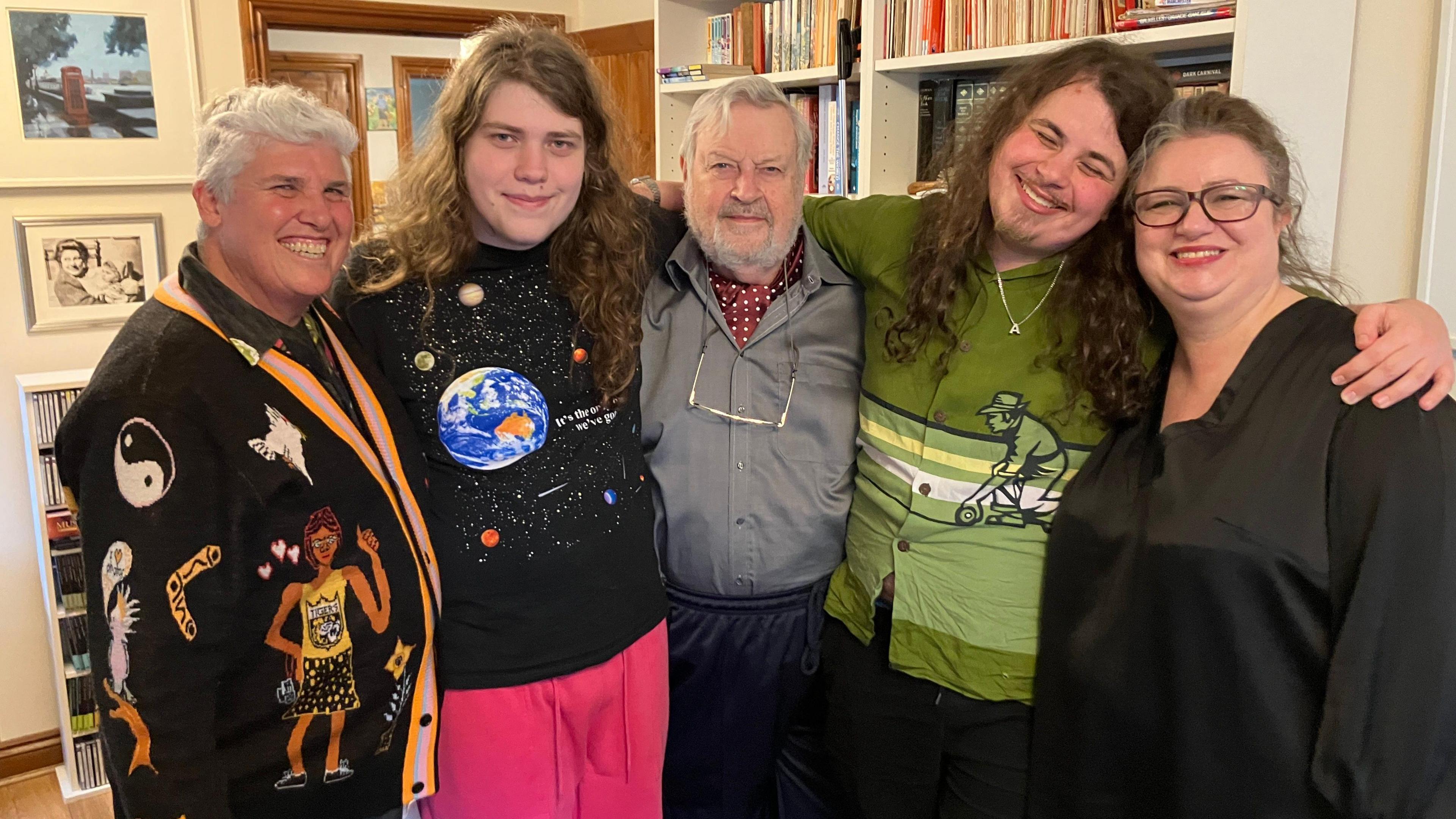 Five people smiling at the camera with their arms around each other. 