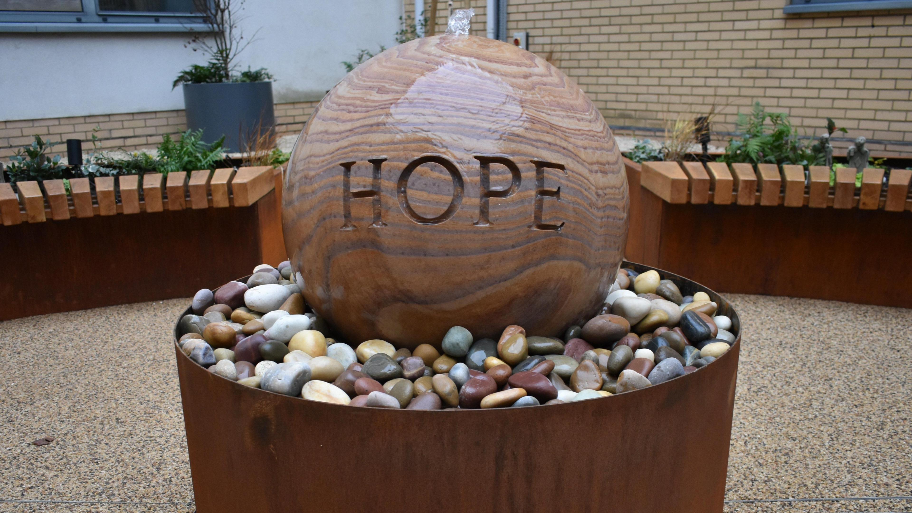 Granite spherical water feature with the word "hope" on the front