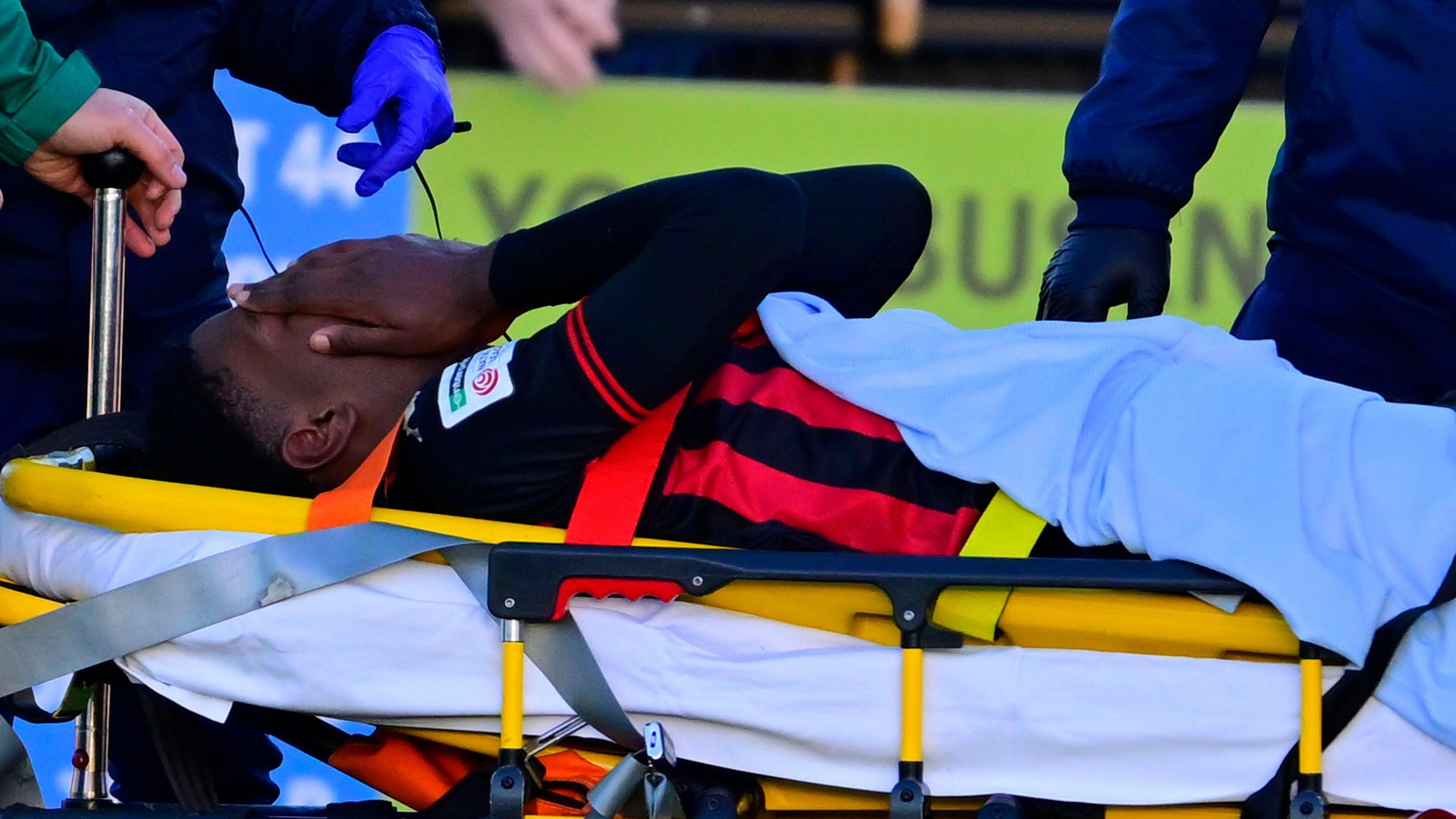 Dominic Johnson-Fisher is taken off on a stretcher