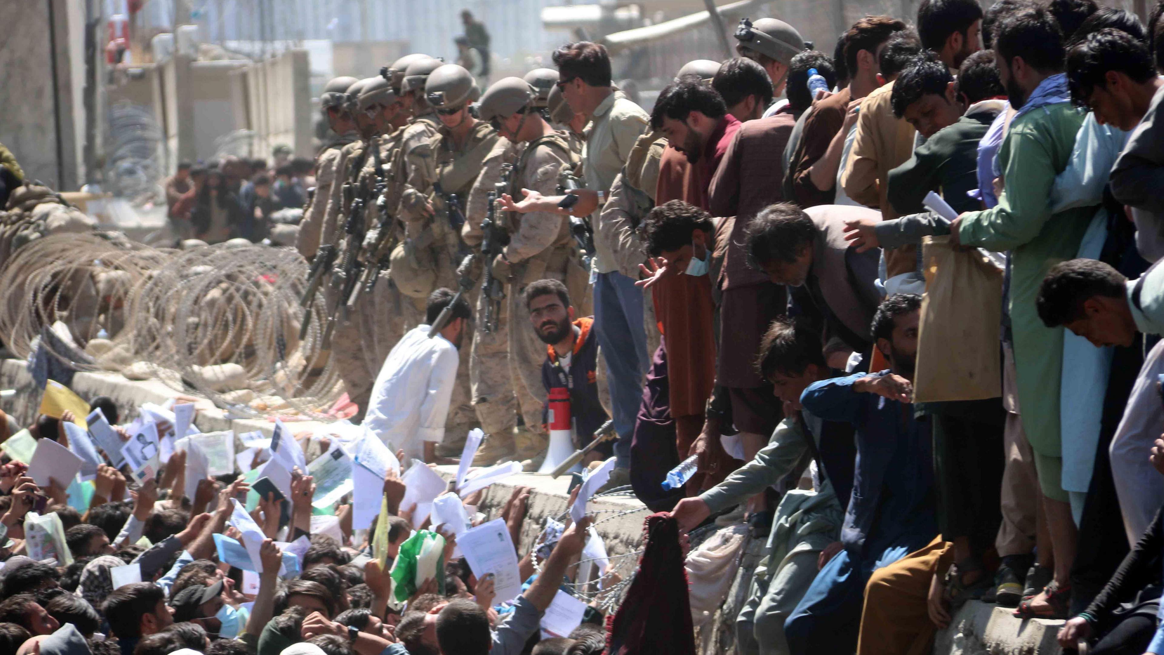 Afghans struggle to reach the foreign forces to show their credentials to flee the country outside the Hamid Karzai International Airport, in Kabul, Afghanistan.