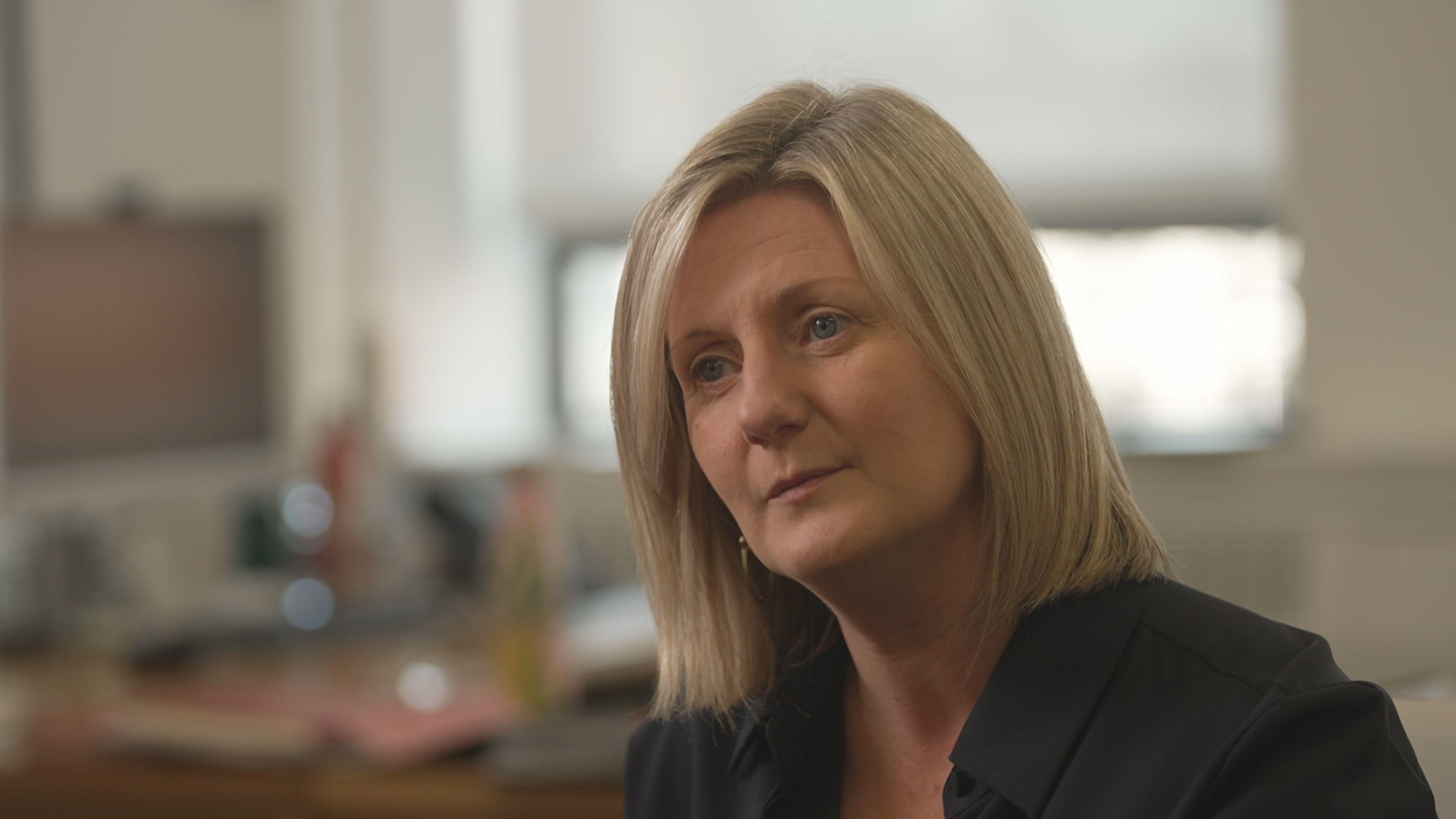 Grainia Long, Chief Executive of the Northern Ireland Housing Executive. She is wearing a black jacket and has medium length blonde hair.