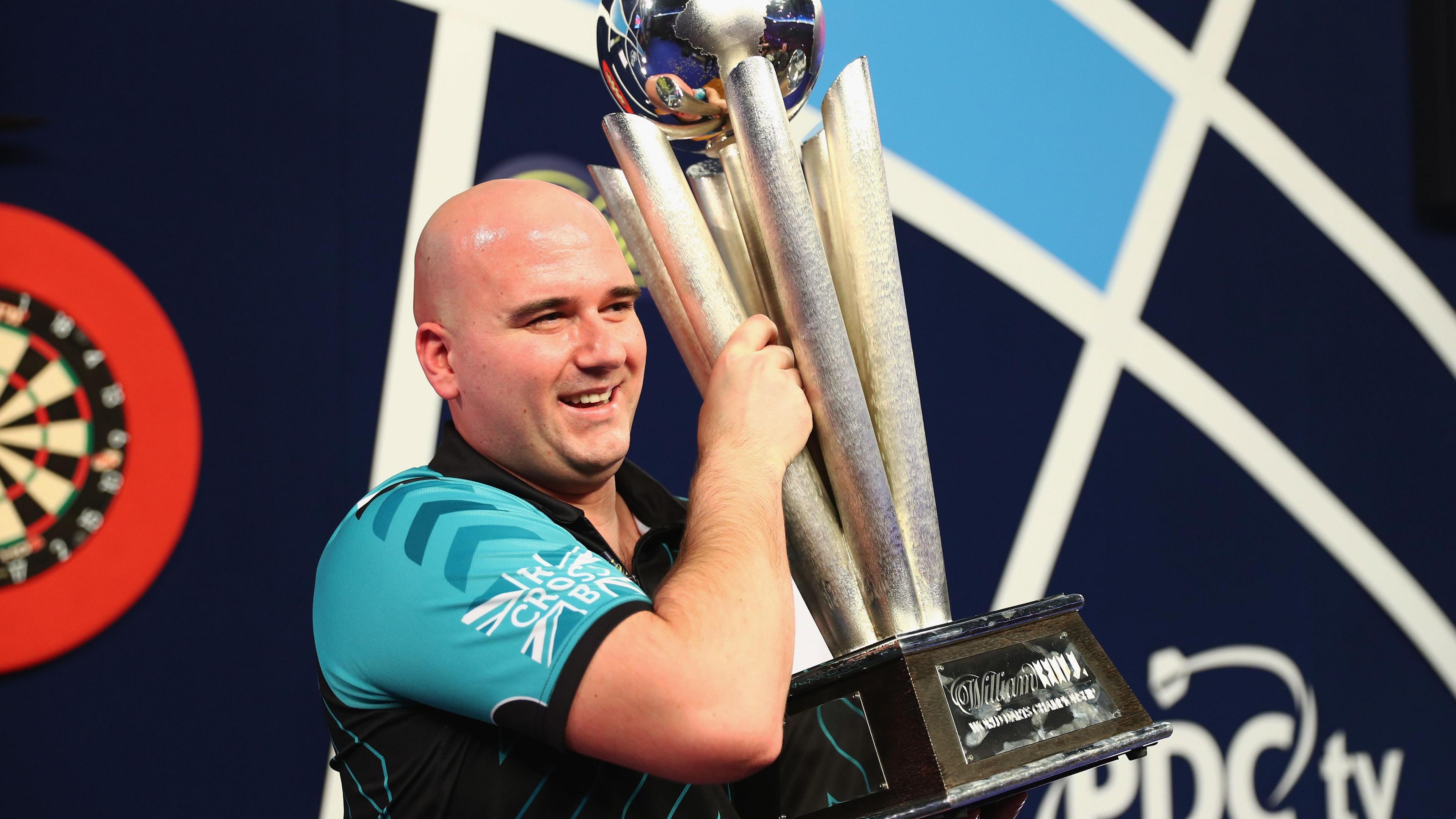 Rob Cross holding the world darts championship trophy.