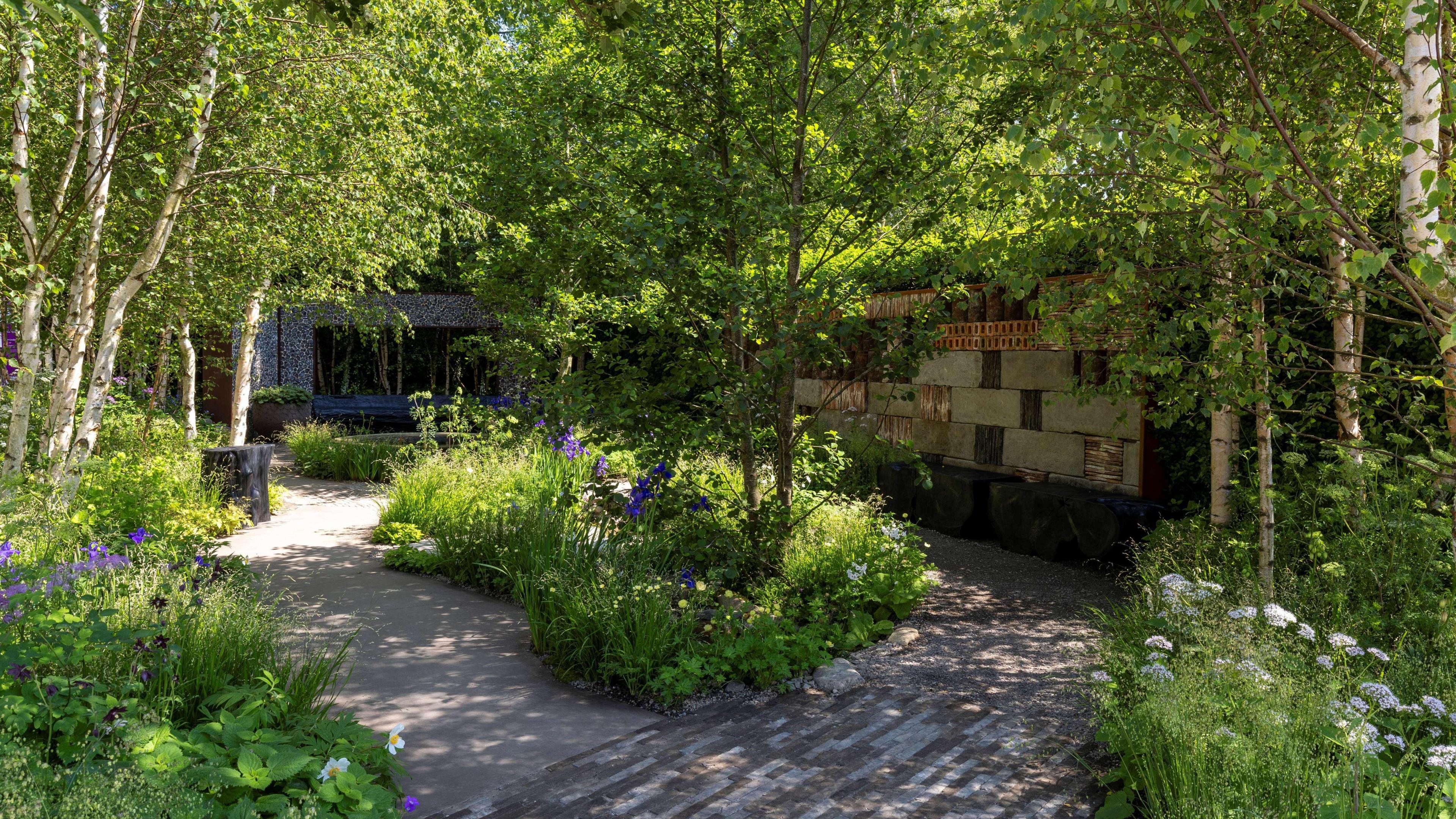 Beautiful garden with purple and white flowers, a water feature and pathways