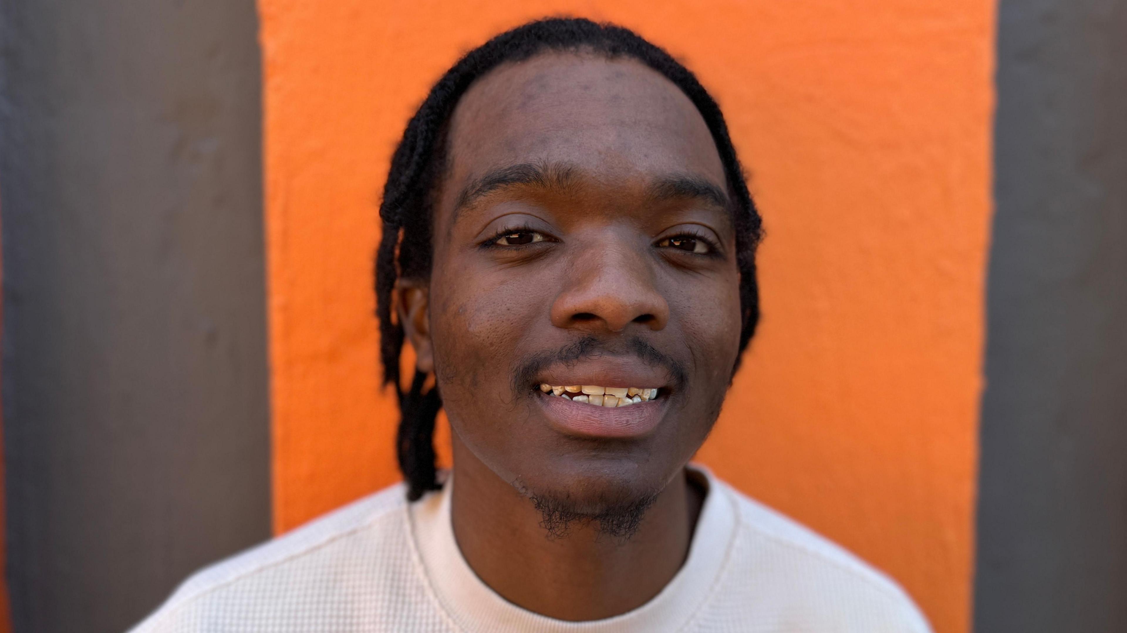 A close up image of Delight Sithole in front of an orange background