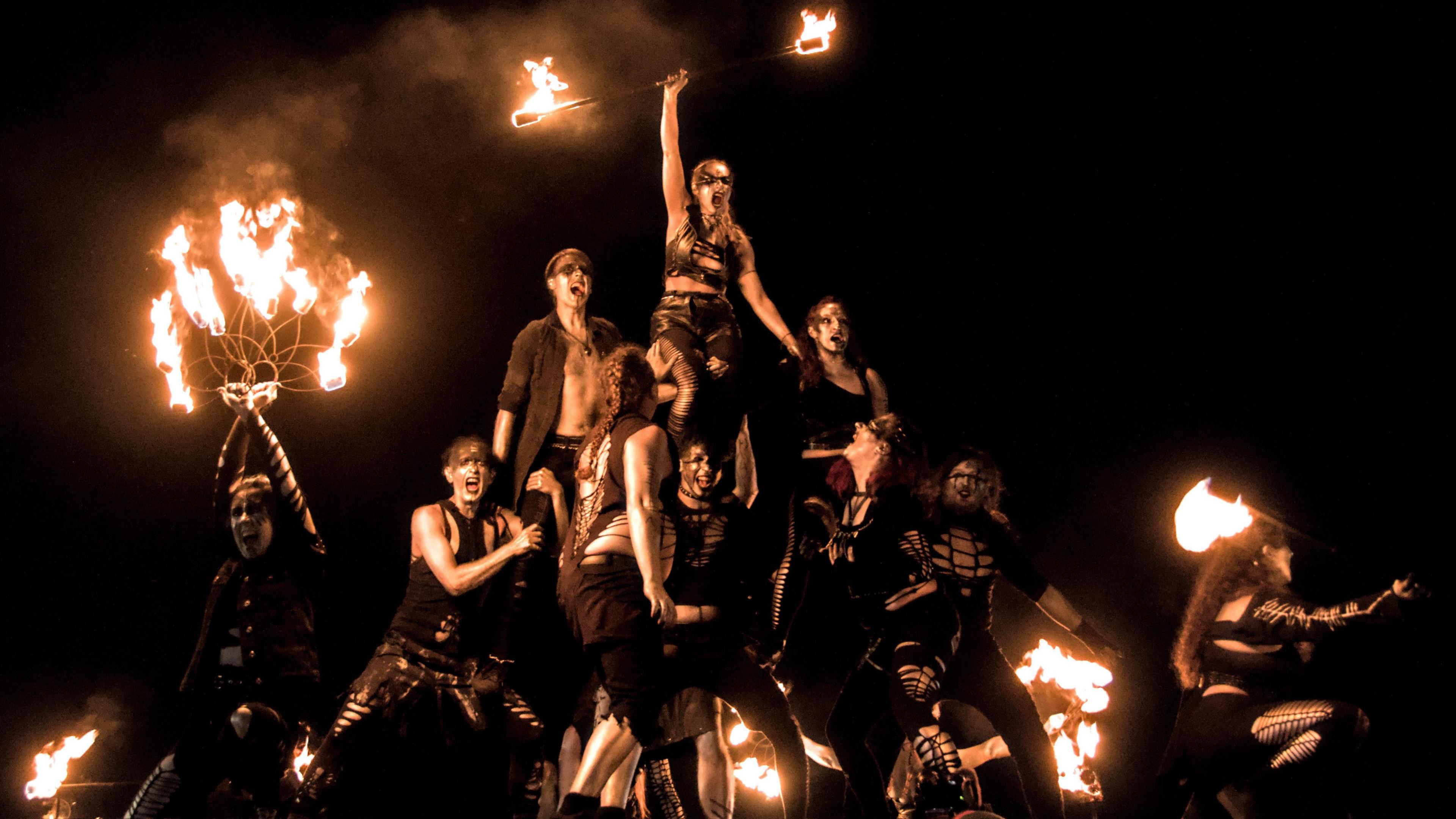 A human pyramid, with performers holding fire