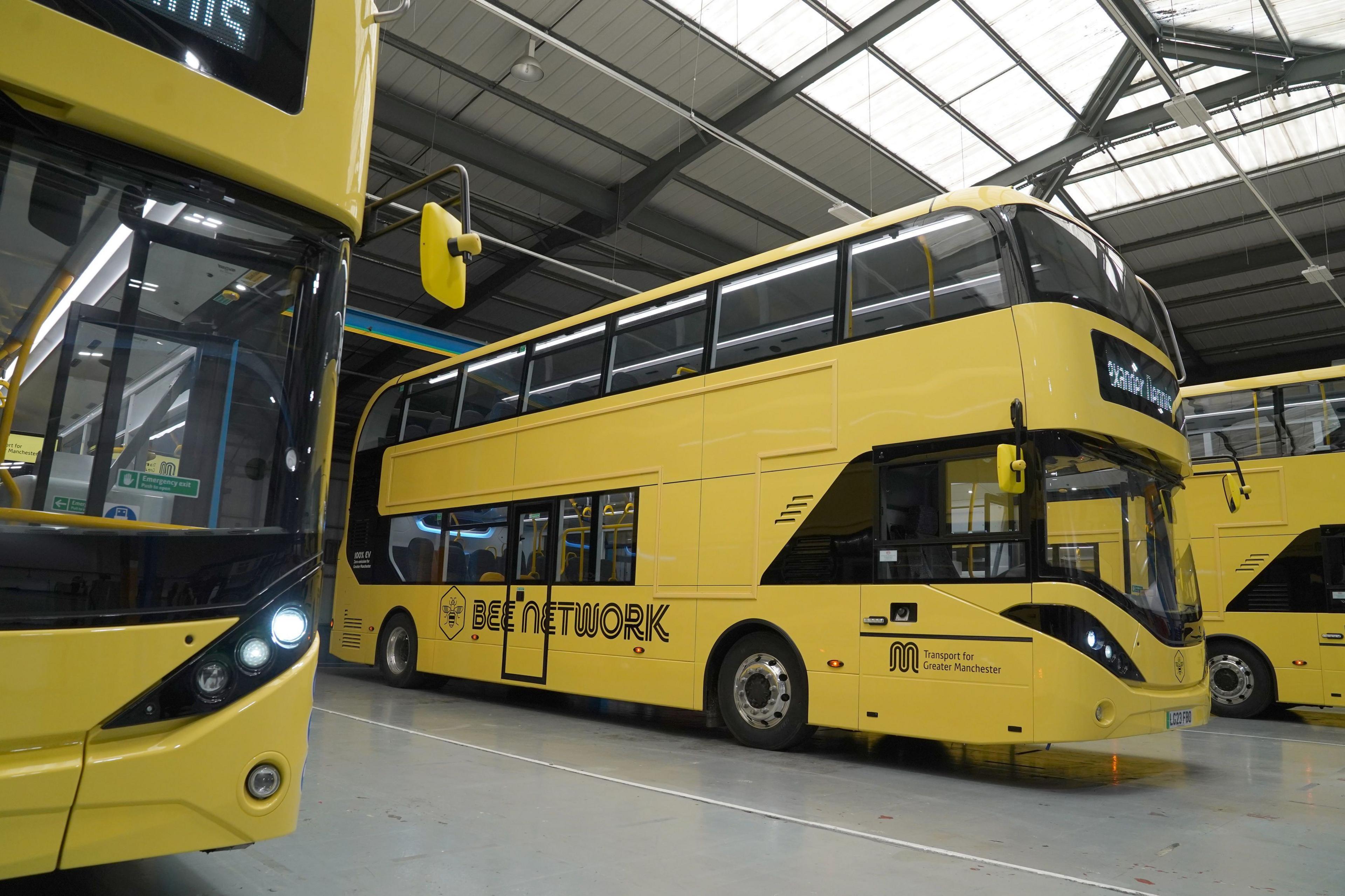 A row of bright yellow Bee Network buses in a hanger.