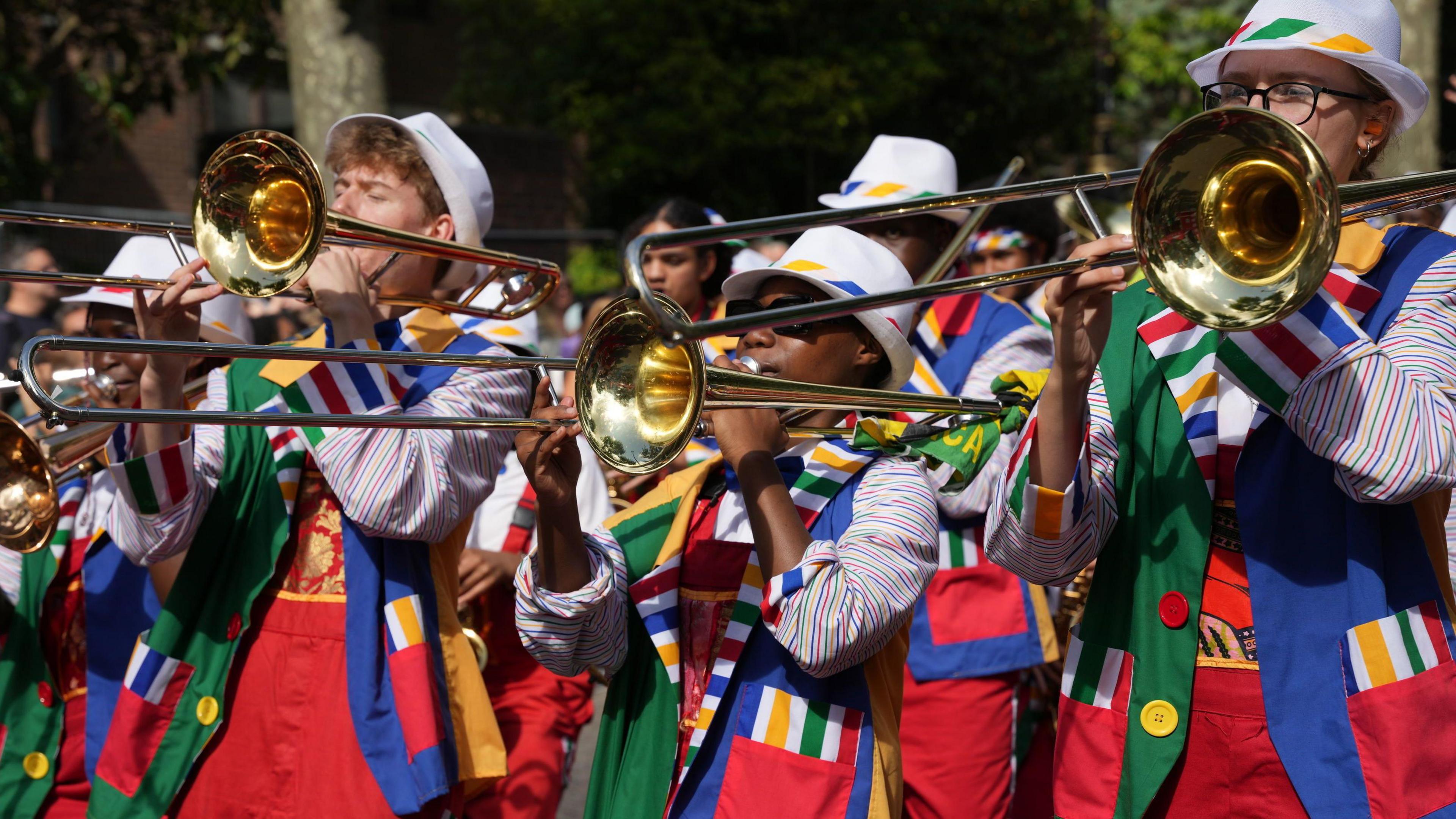 A band featuring people playing the trombone and wearing colourful uniforms in the Children's Day Parade