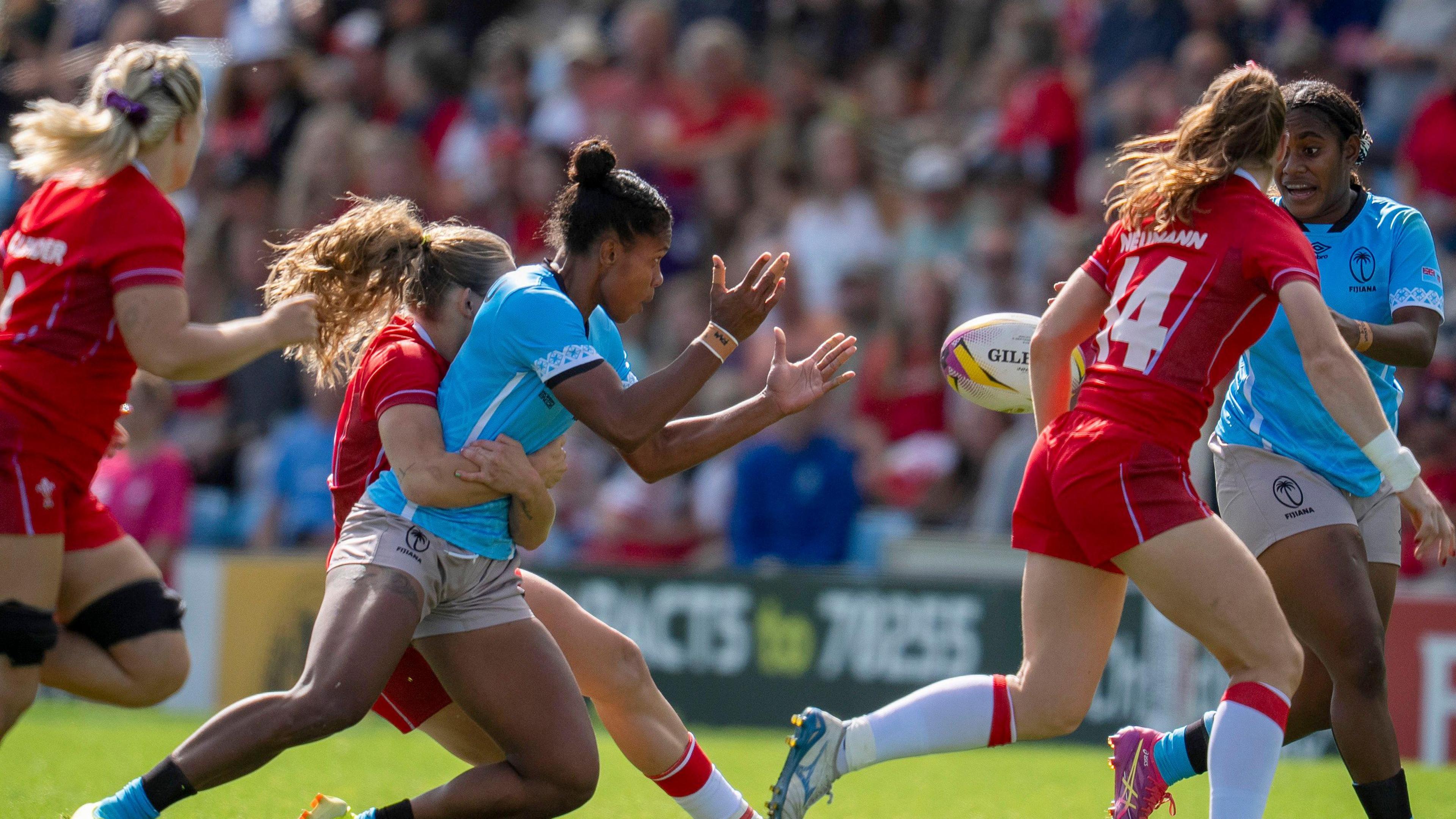 Players during the Women's Rugby World Cup 2025 at Sandy Park, Exeter. Women in Rugby Uniform. The ball is being thrown. There are people in the stands and are blurred.