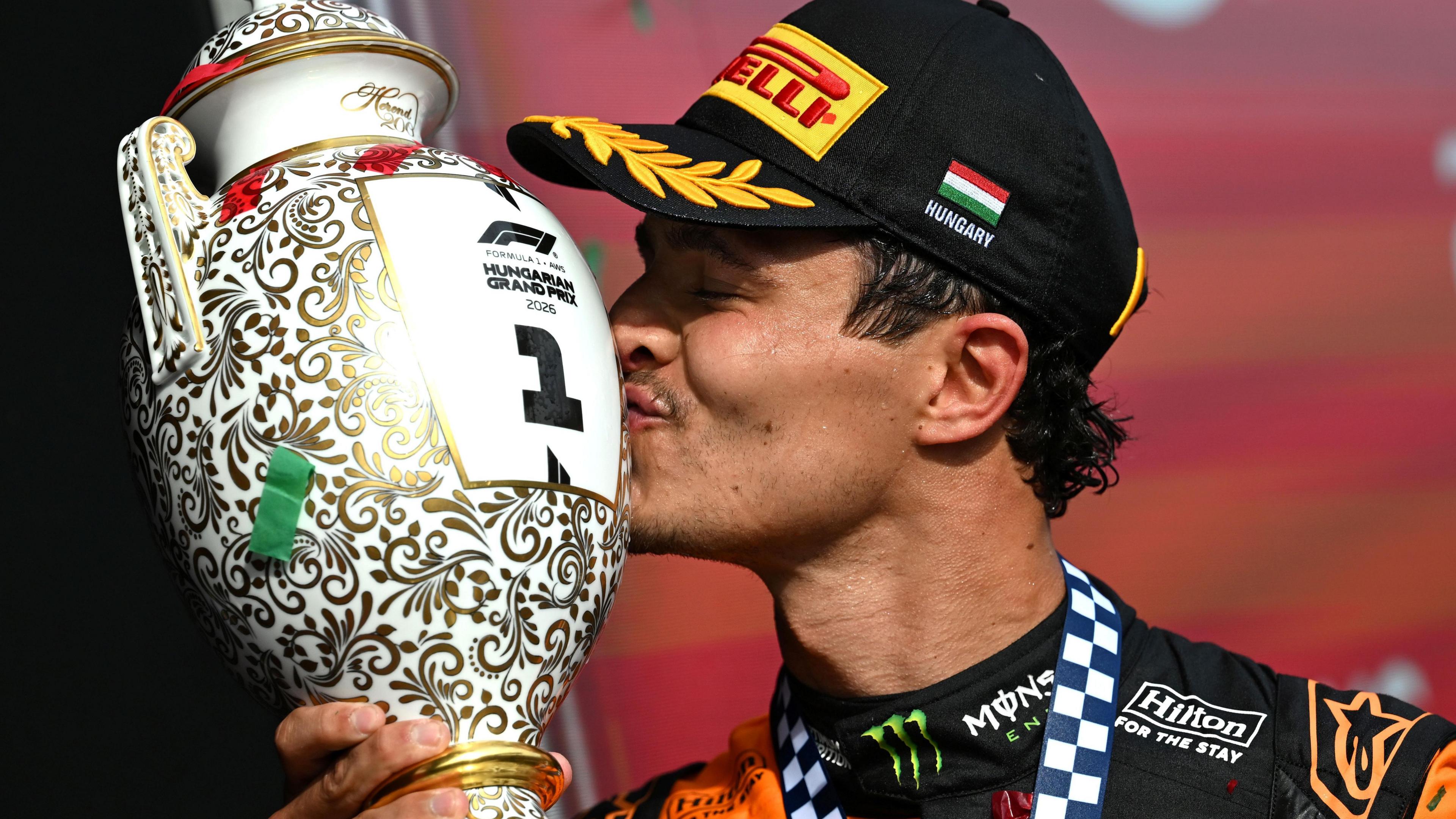 McLaren's Lando Norris kisses the winner's trophy on the podium at the Hungarian Grand Prix