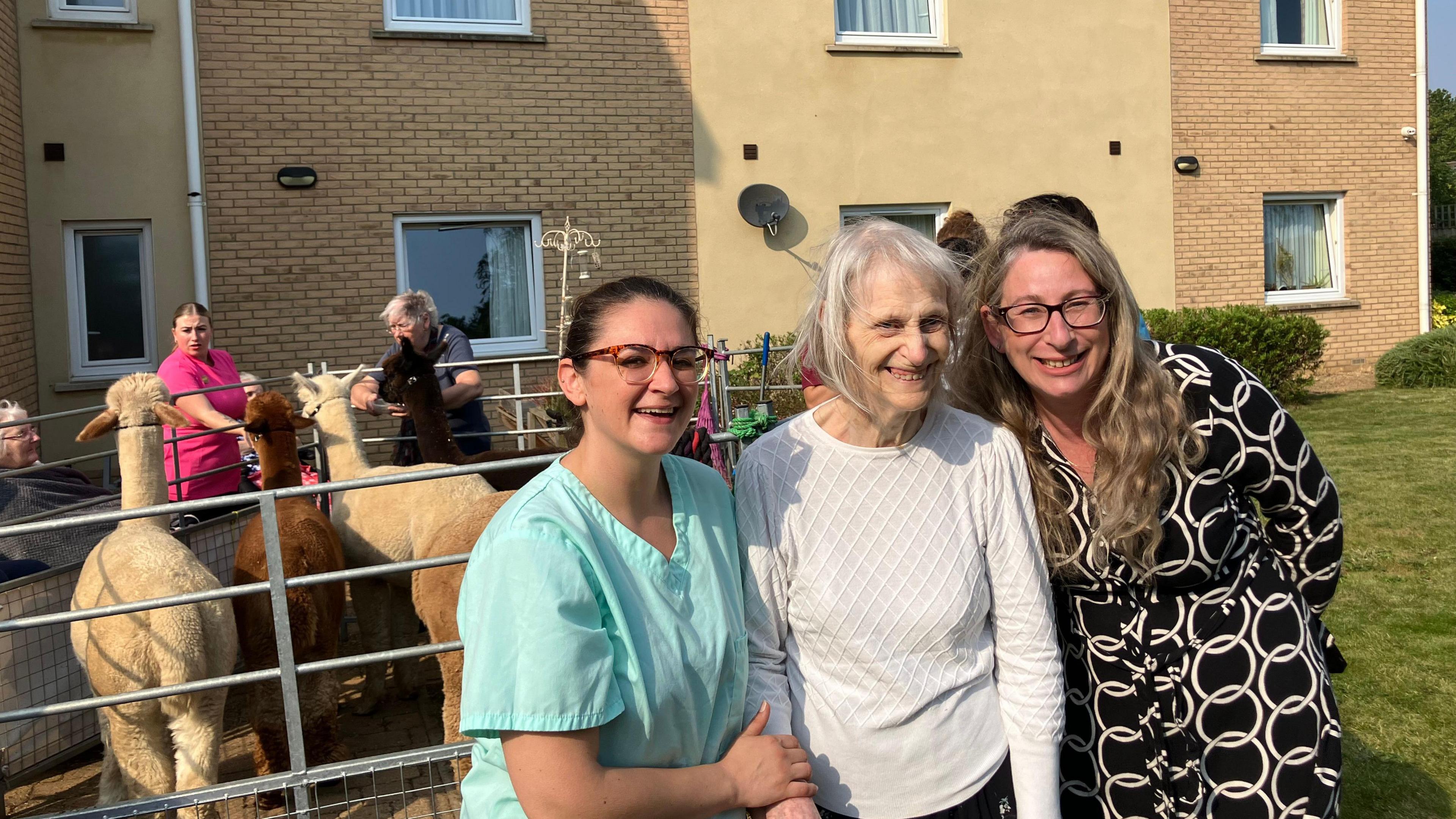 Laura in a blue shirt with a residents wearing a white cardigan and Natalie in black and white dress.