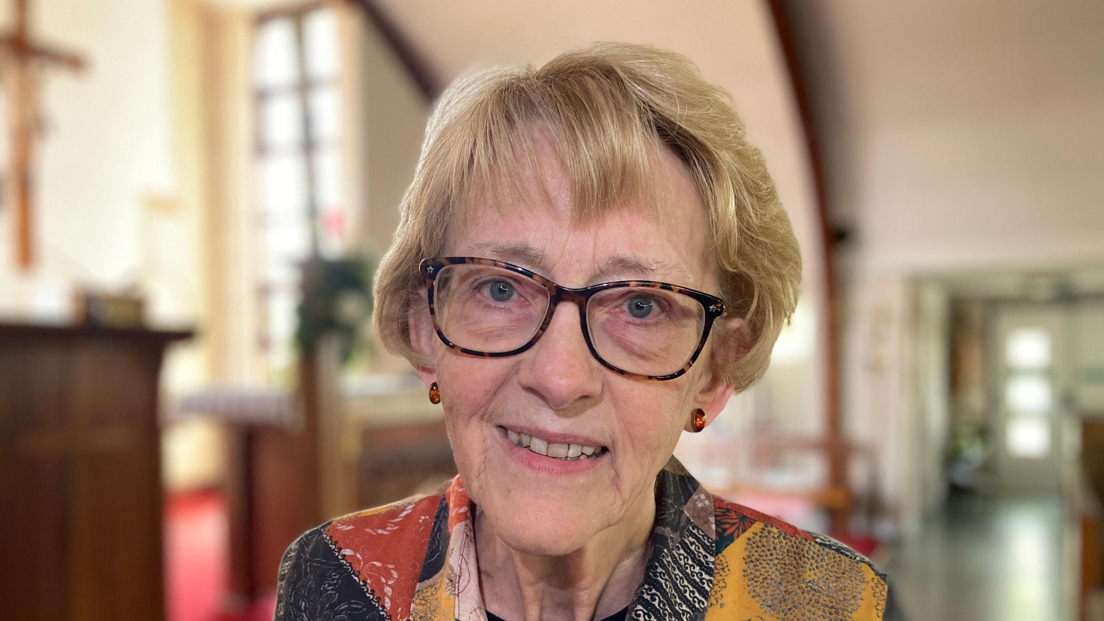 A close-up shot of Kathy Goodwin. She is smiling, looking into the camera and wearing glasses.