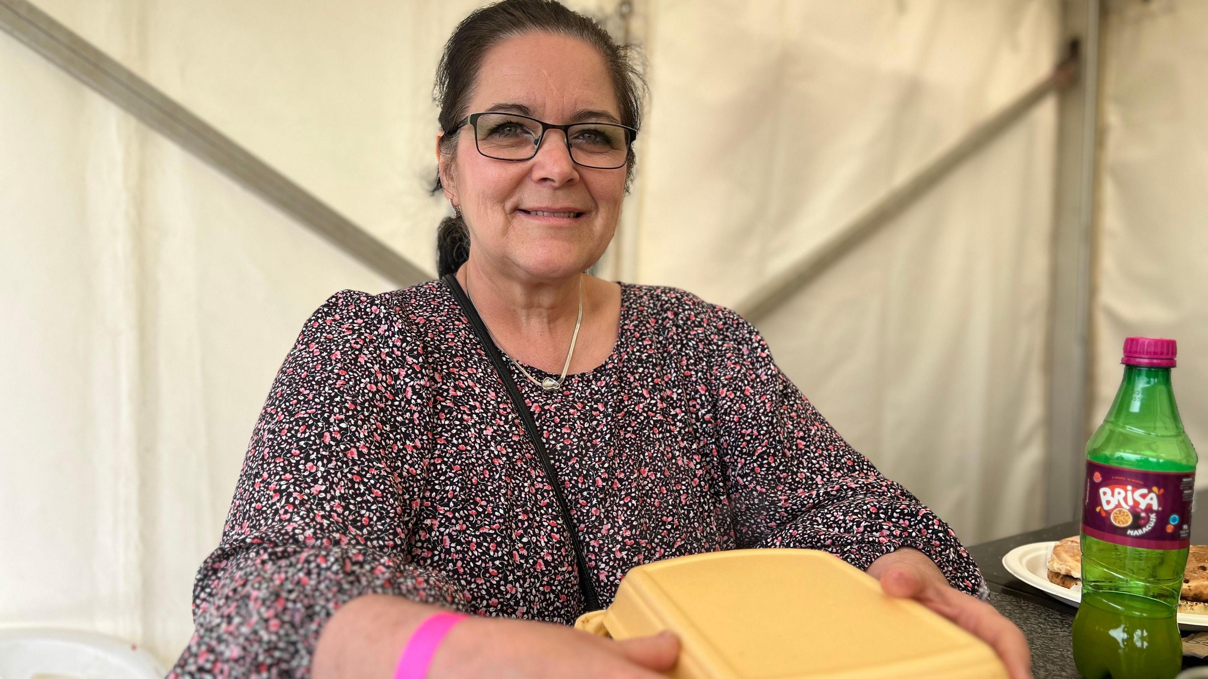 Alcinda smiles at the camera as she holds a box of food