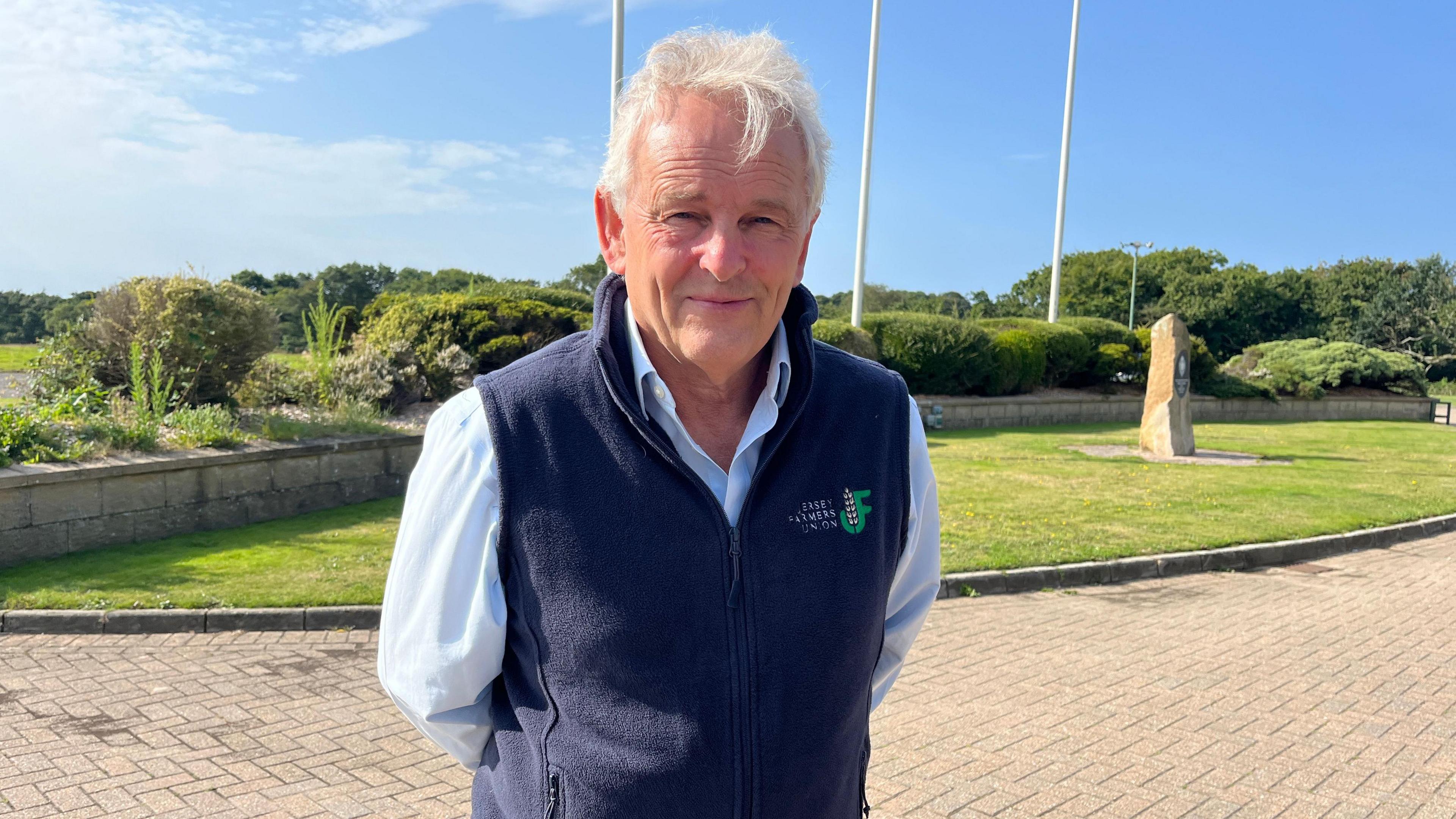 Doug Richardson, in a dark blue gilet and blue shirt, standing outside the RJ&HS Trinity Showground.