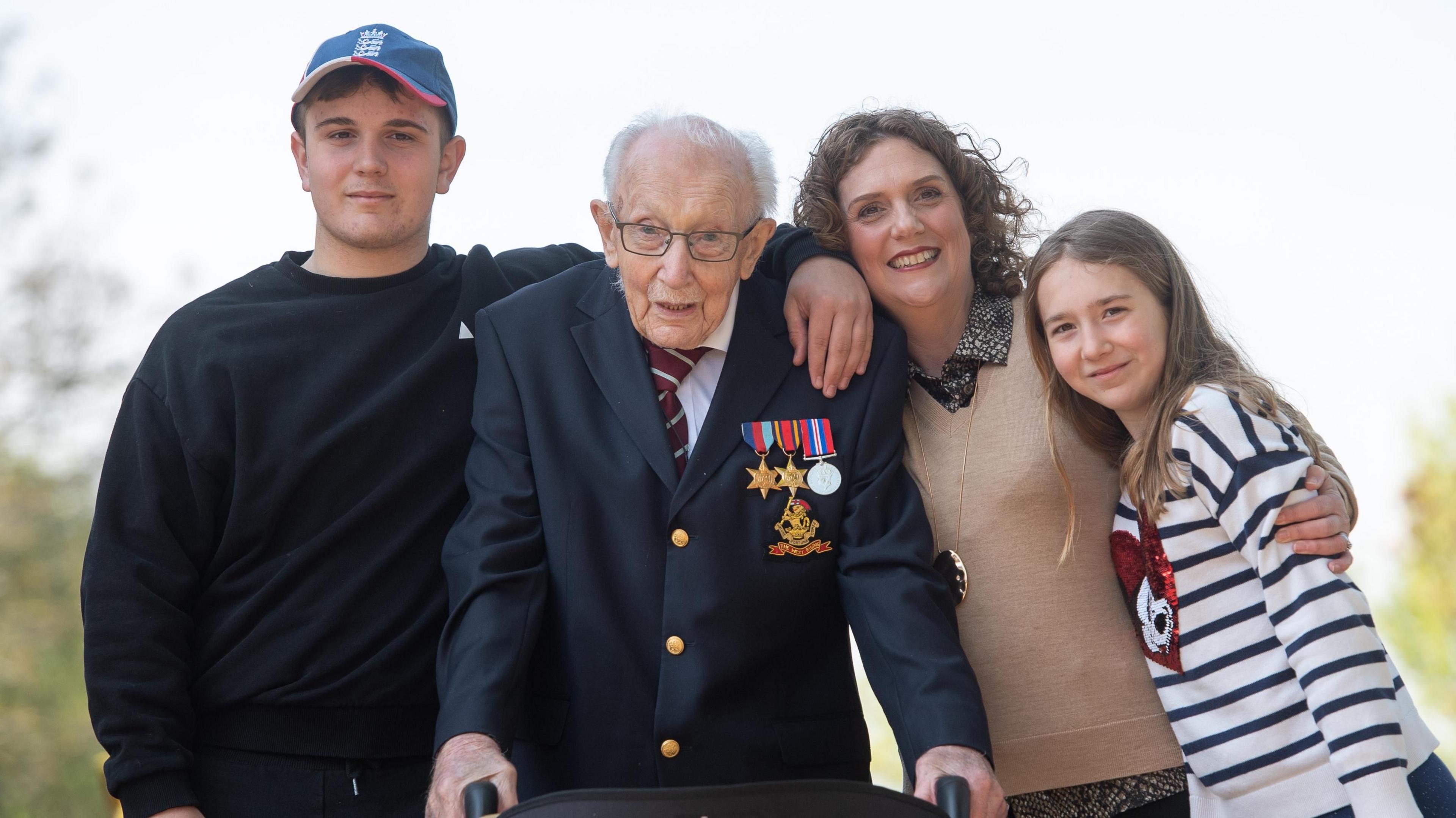 99-year-old war veteran Captain Tom Moore, with (left to right) grandson Benji, daughter Hannah Ingram-Moore and granddaughter Georgia, at his home in Marston Moretaine, Bedfordshire, after he achieved his goal of 100 laps of his garden