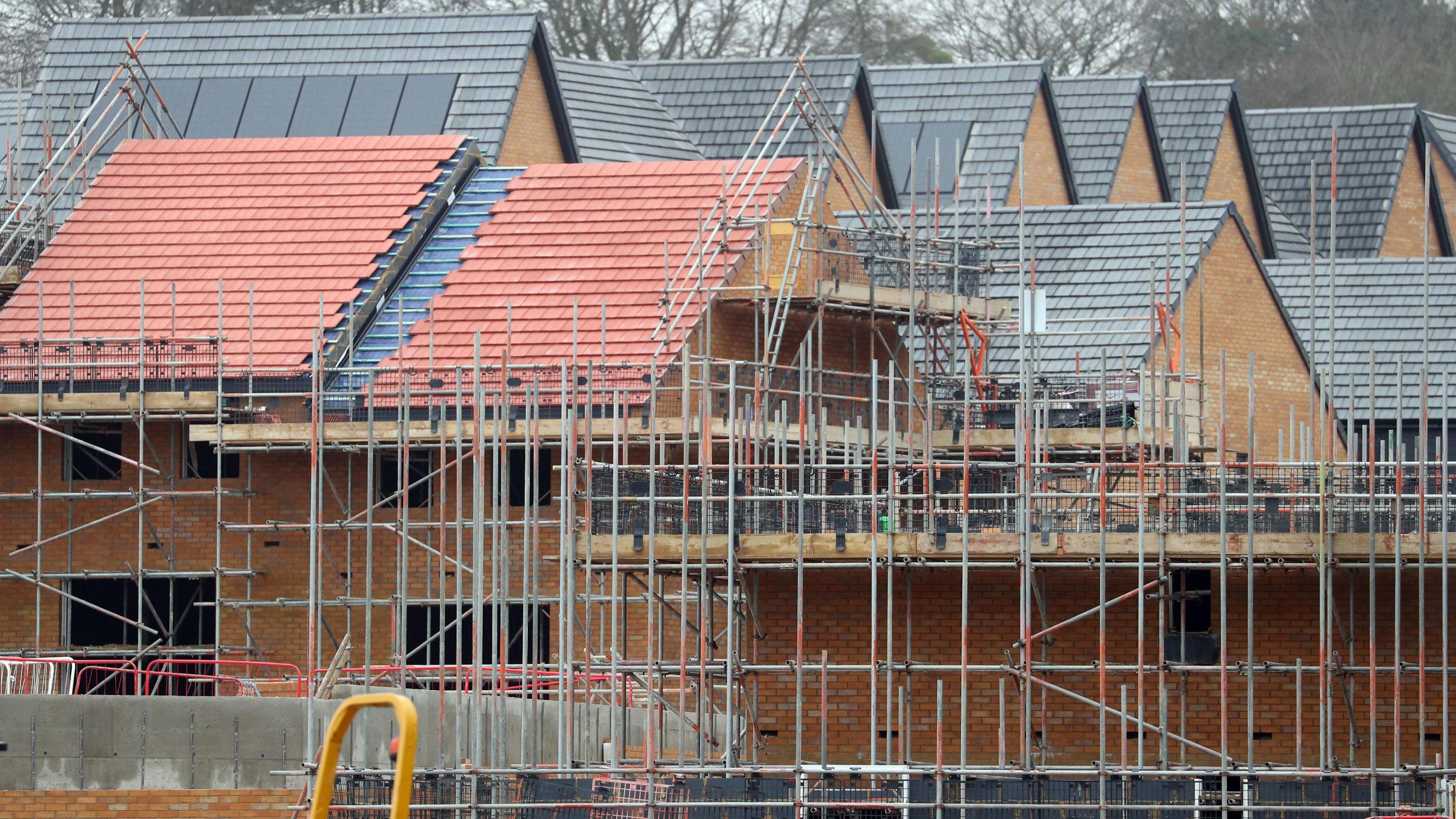 A stock shot of part-built houses with scaffolding in front of them.