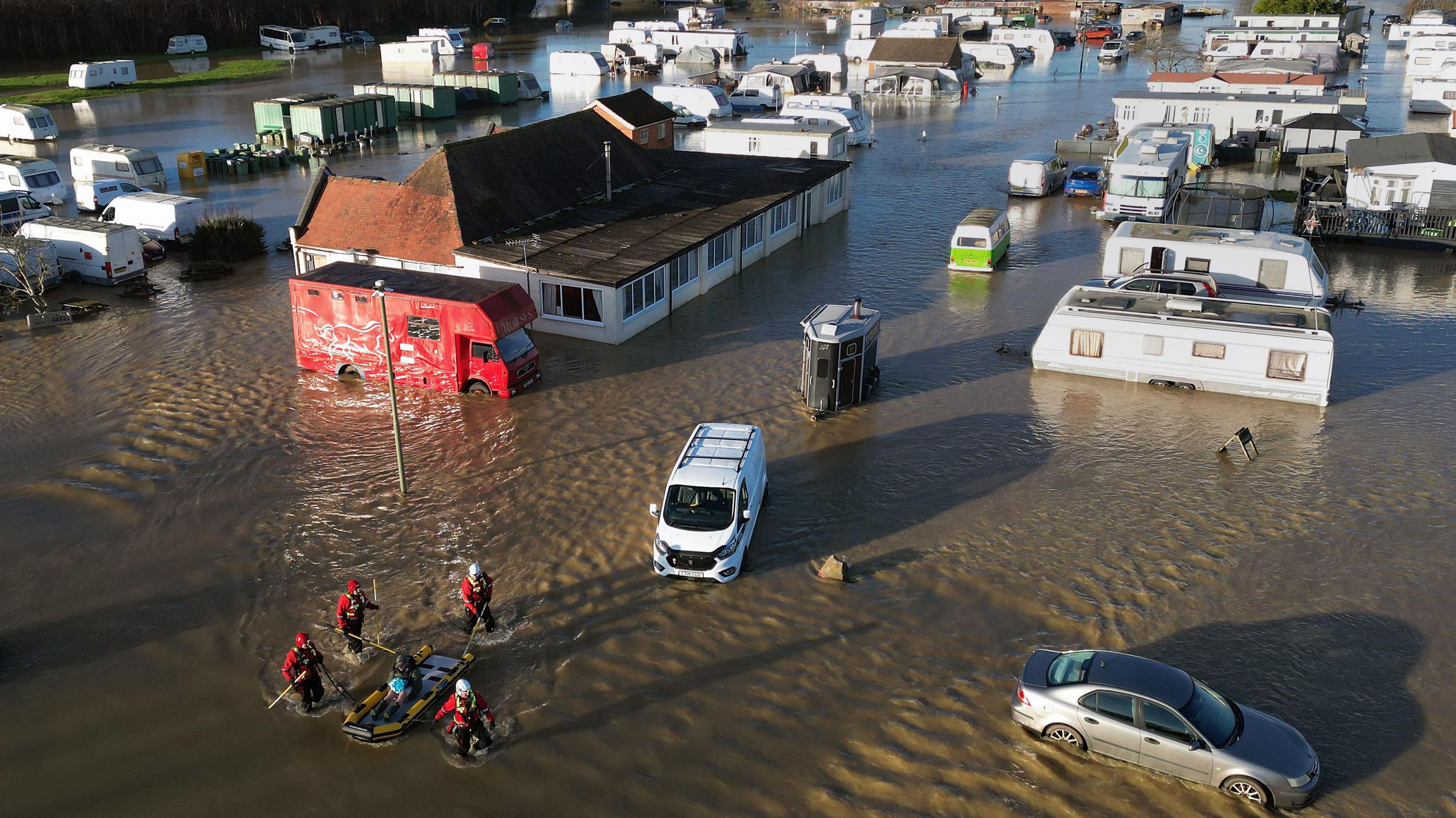 An aerial view of a flooded caravan park as a man is rescued.