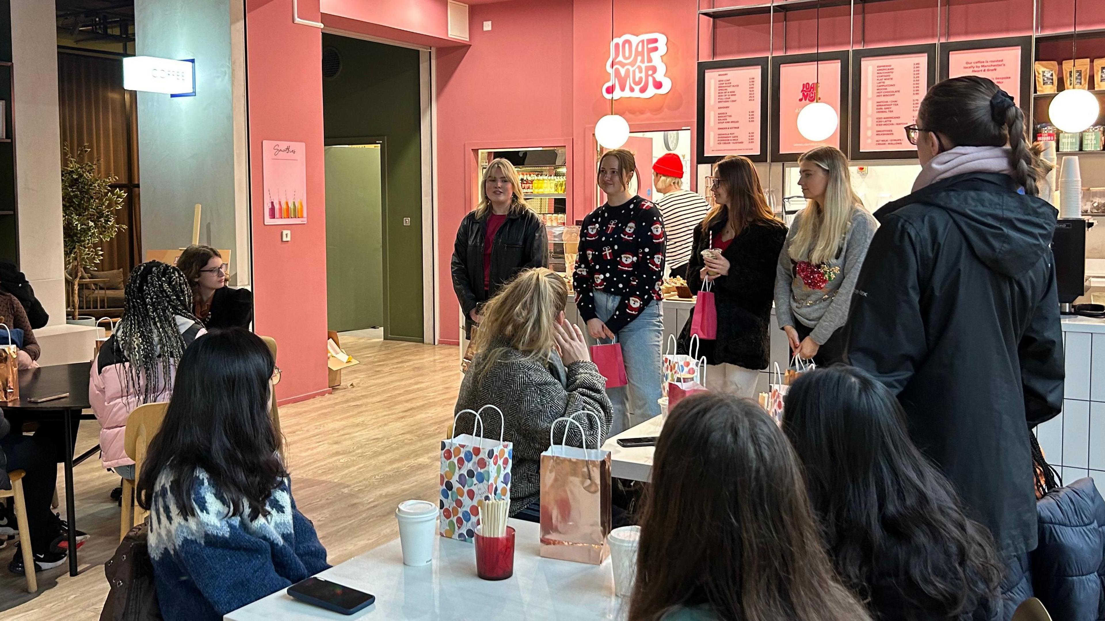 Girls giving a talk to a few tables of women