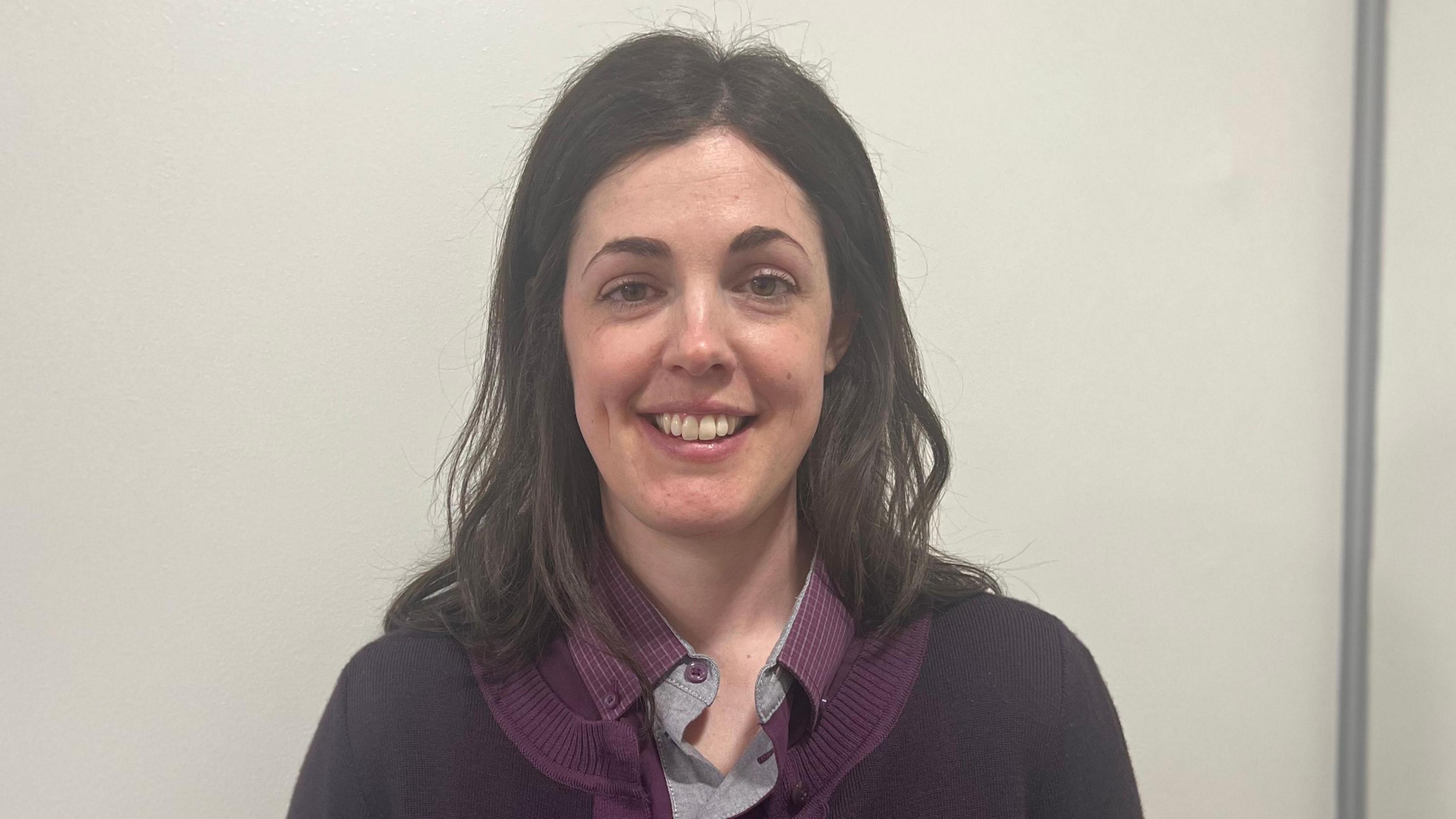 Train driver Elizabeth Kirby with shoulder length brown hair and wearing a purple polo top with a grey collar