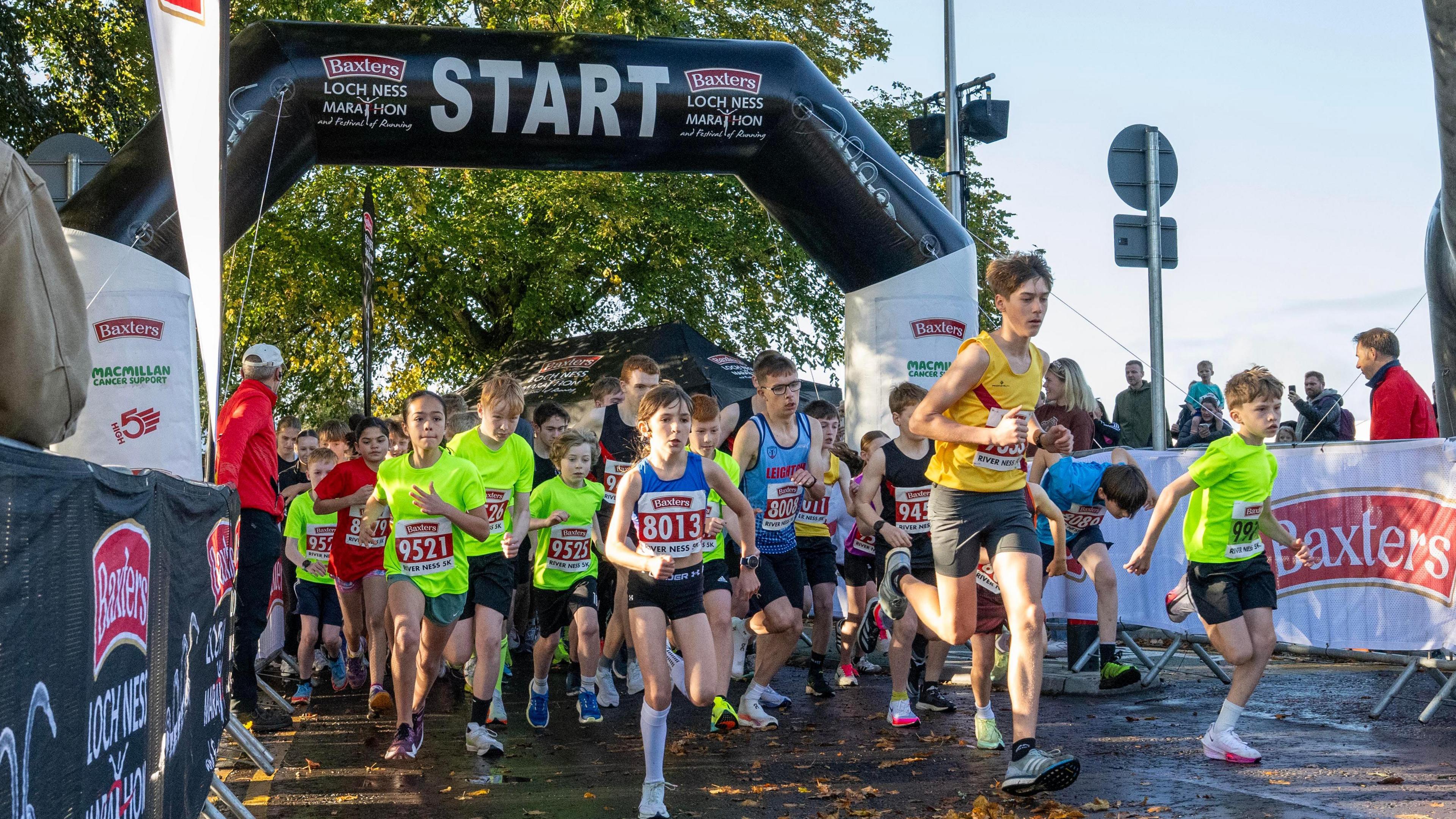 dozens of younger people run through the start gate