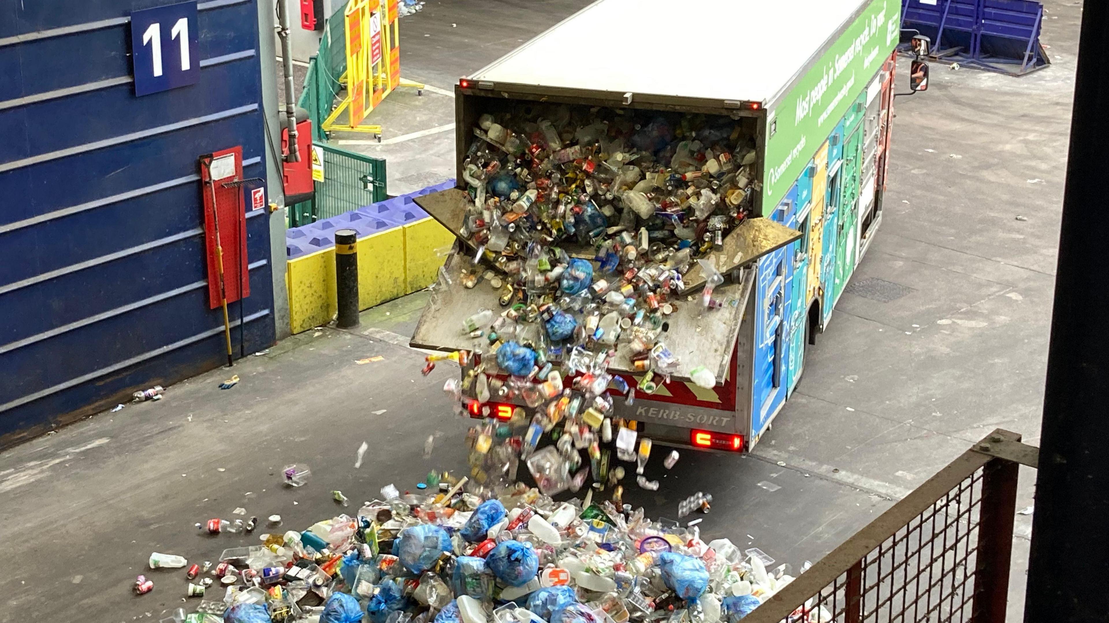 Recycling van with back door open. There is tonnes of rubbish pouring out of the back of van