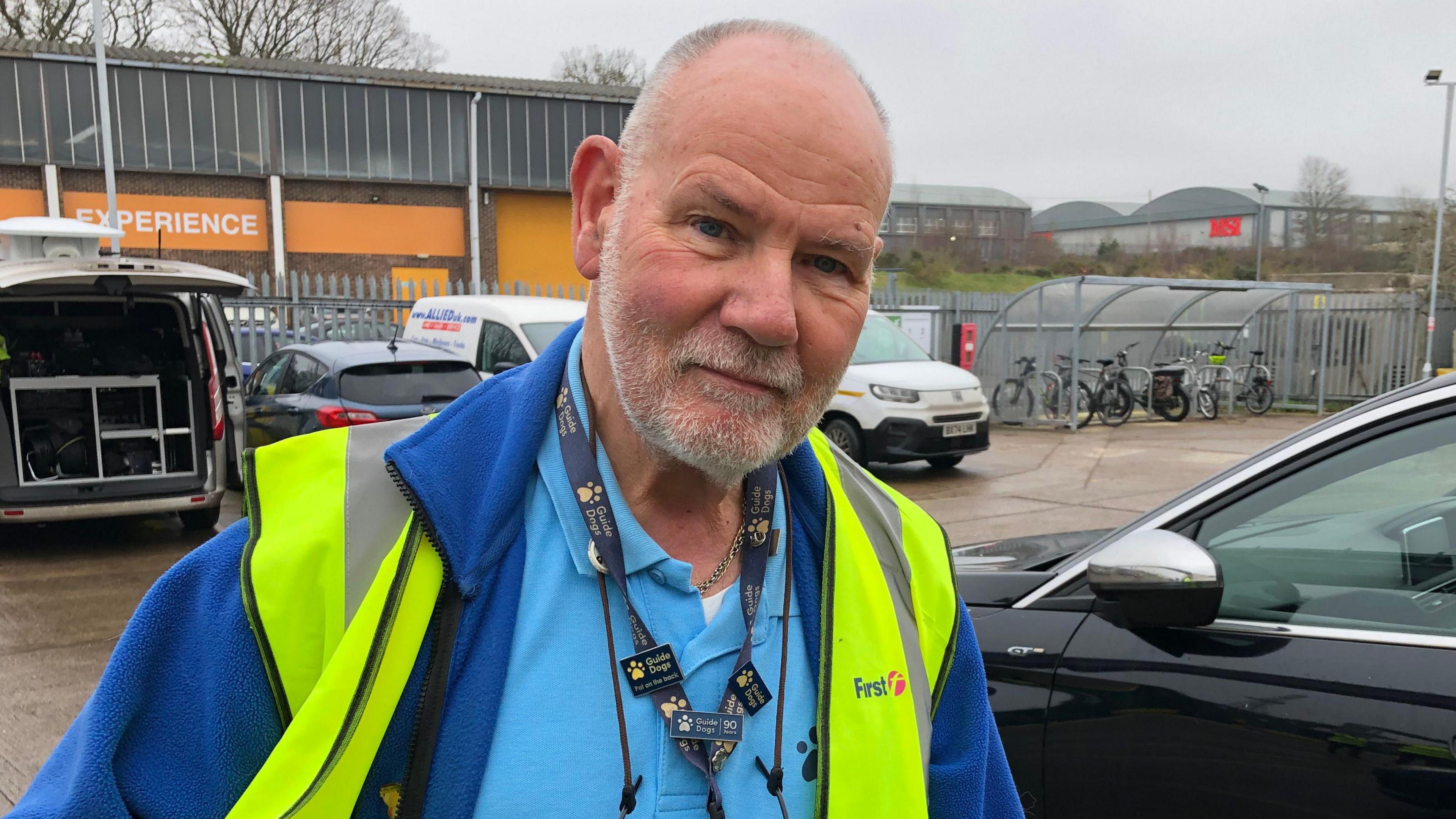 Richard Bussien, a man who is looking at the camera. He is wearing a blue top and darker blue fleece and a fluorescent hi-vis jacket. 