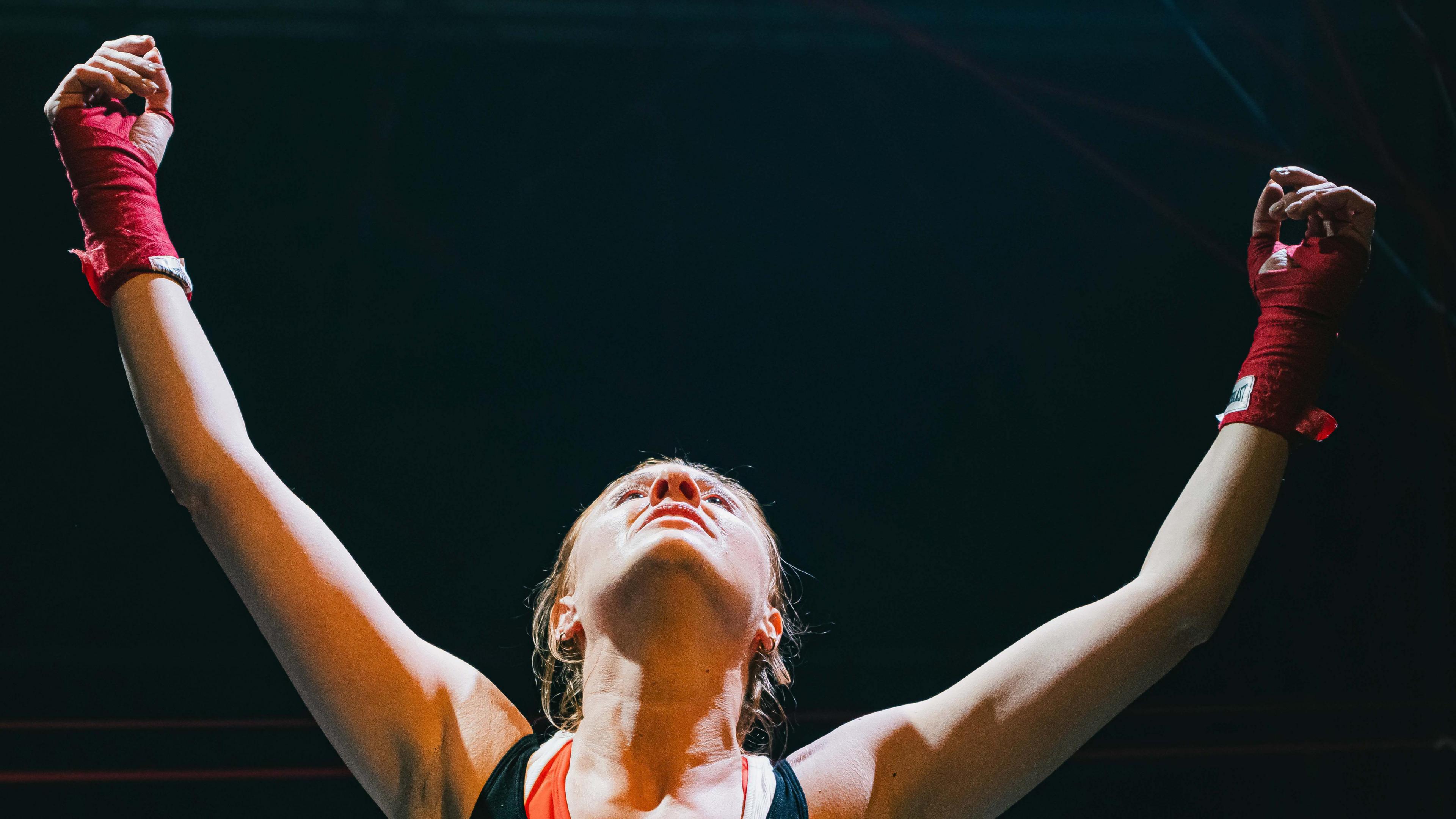 Actress Katie Payne on stage with her harms raised in the air