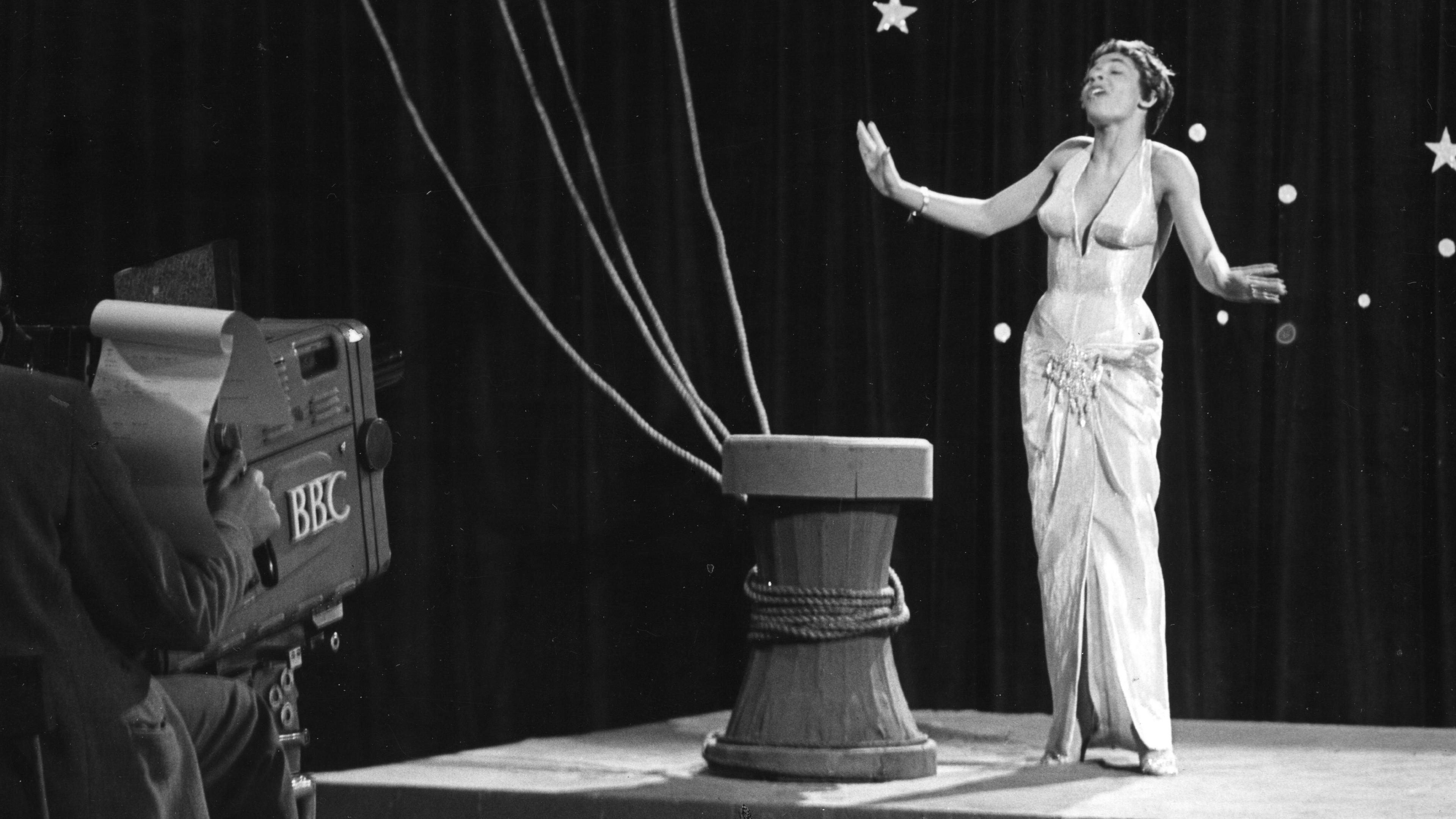 Shirley Bassey standing on stage in front of a BBC camera in 1957