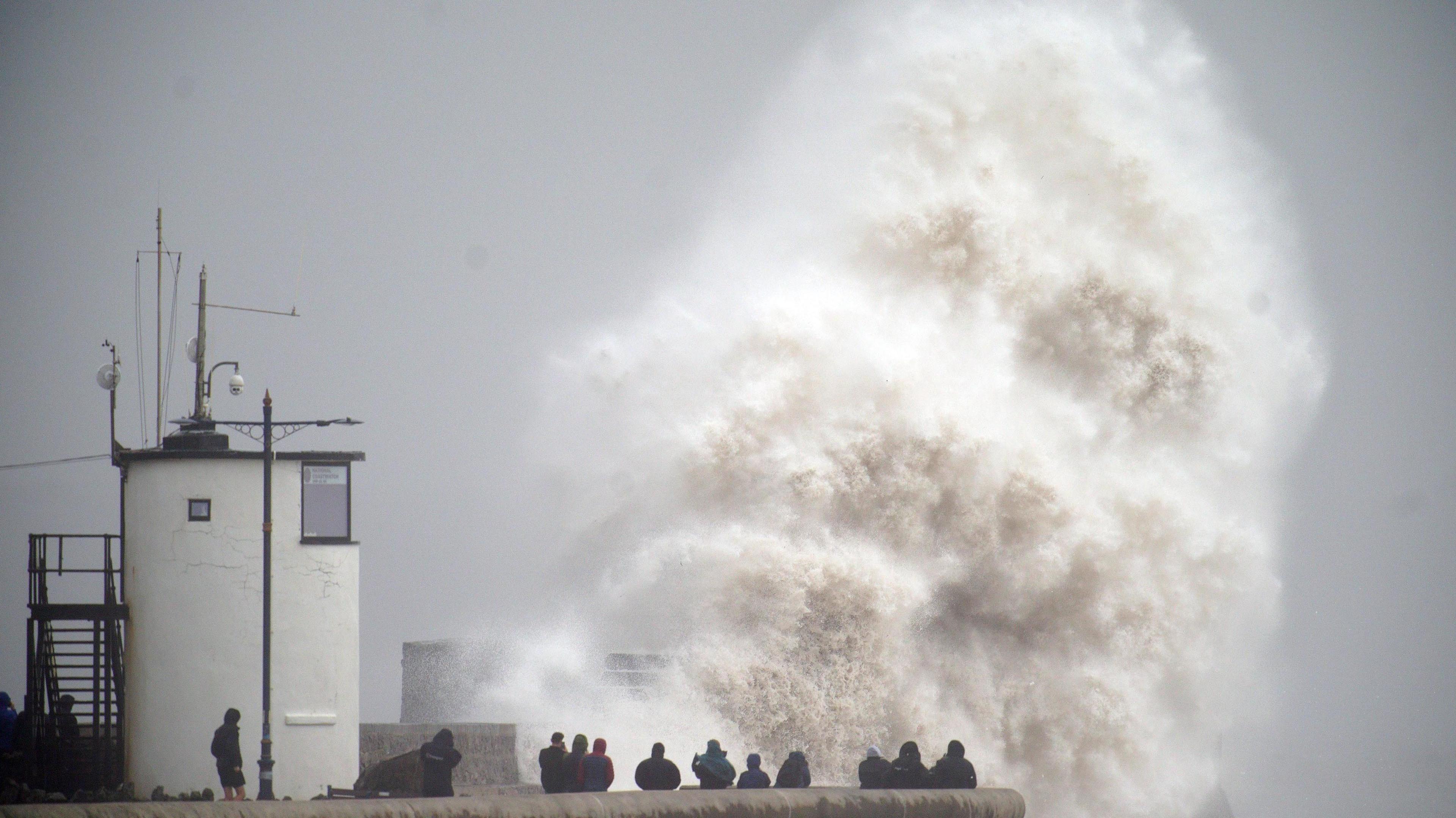 Huge wave crashes into wall as people watch