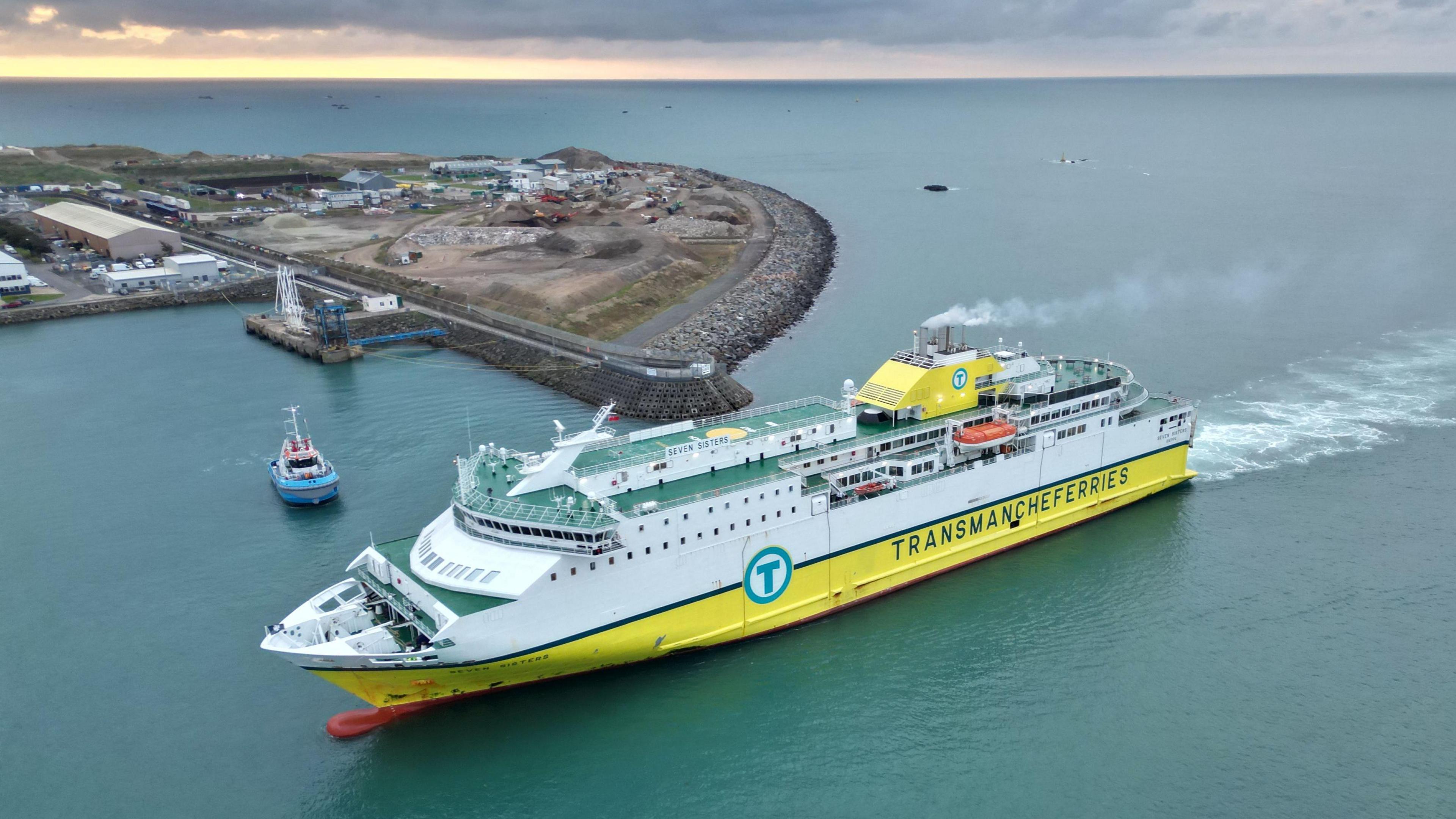 Ferry with a tugboat nearby heading towards a berthing trial in Jersey's St Helier Harbour