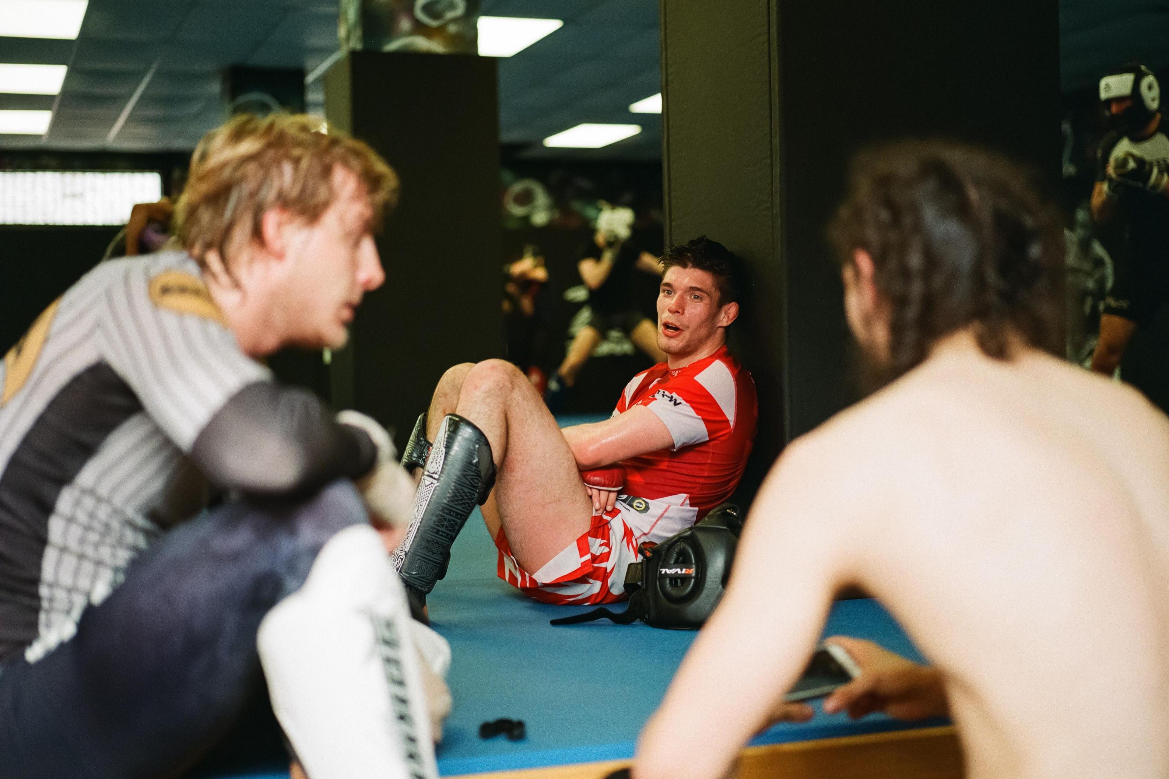 Paddy Pimblett, Adam Cullen and other fighters sit and chat on training mats