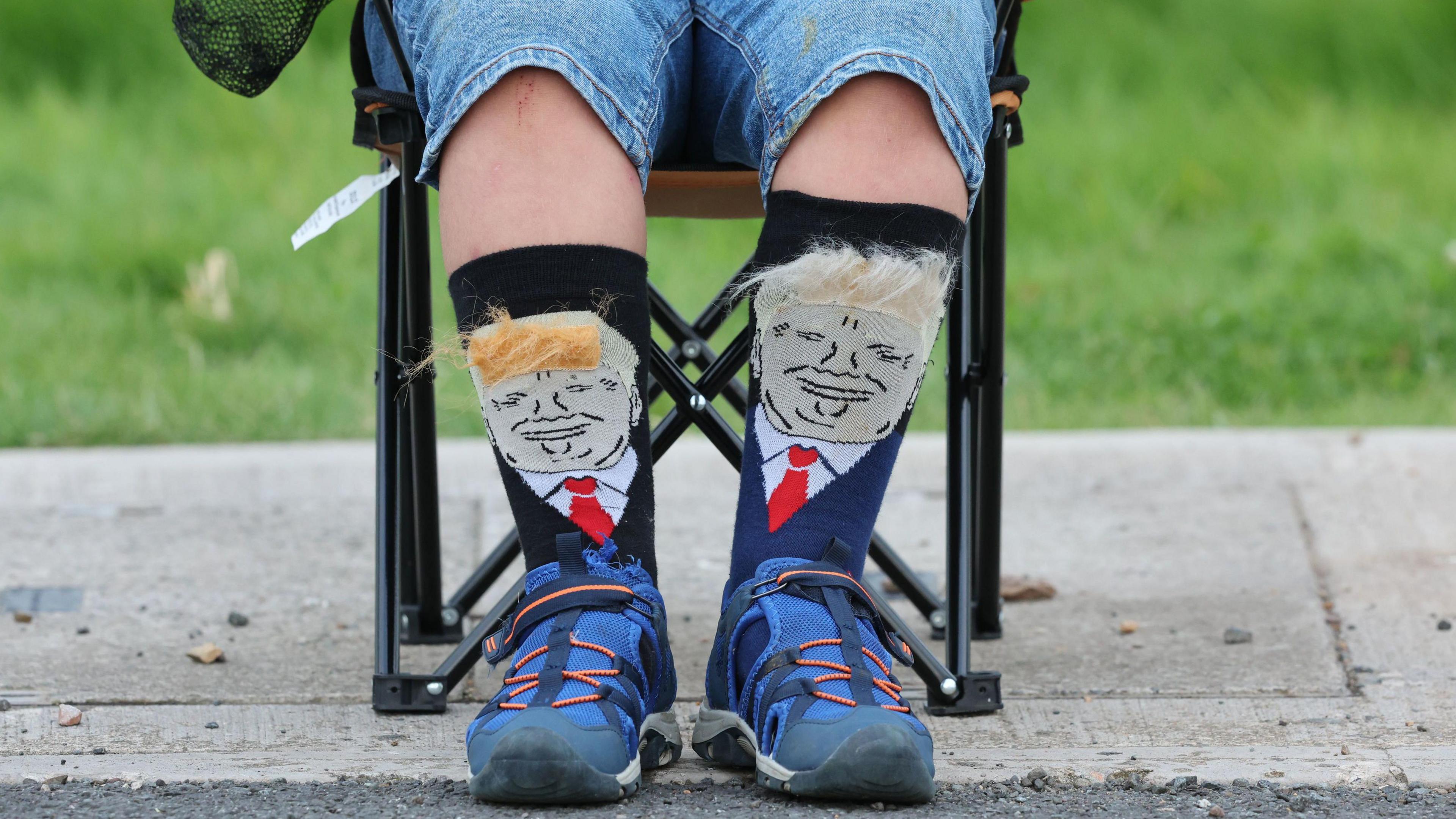 A person wears socks with US President Donald Trump on them, as crowds await the president's arrival at his Turnberry golf course in South Ayrshire.