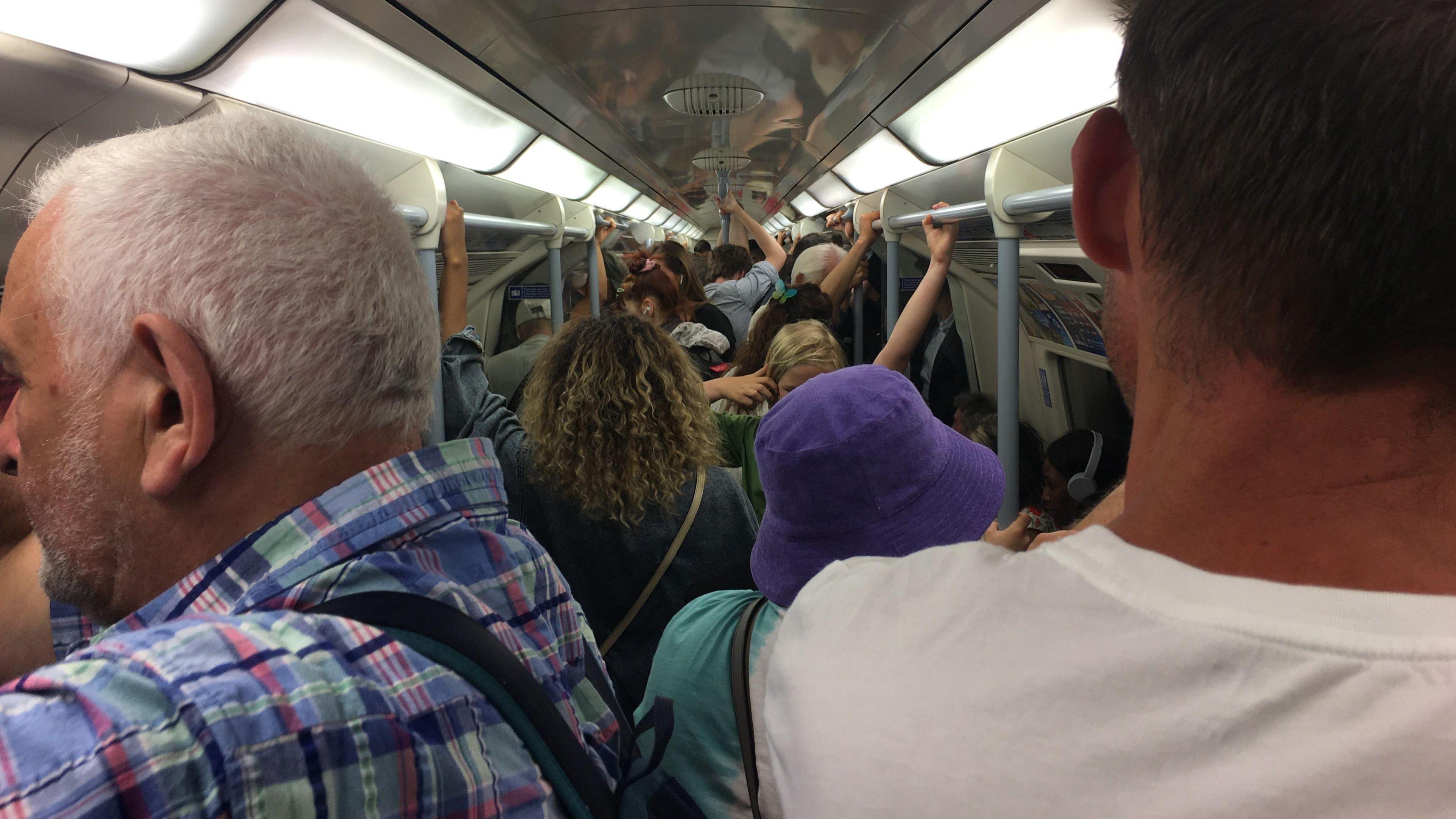 Tube train full of passengers holding the rails