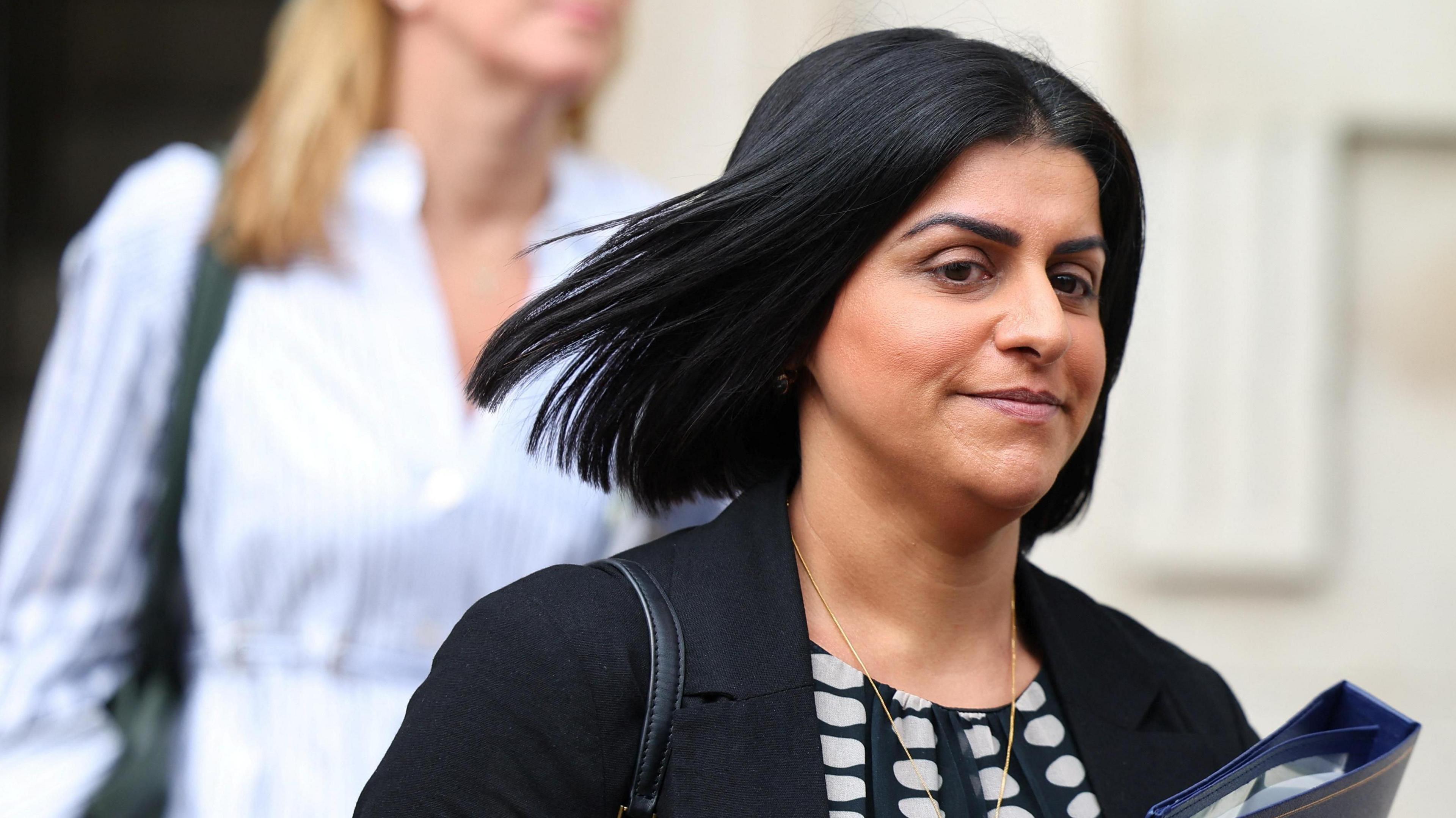 Shabana Mahmood, with hair flying in the wind, clutches a blue folder in Downing Street