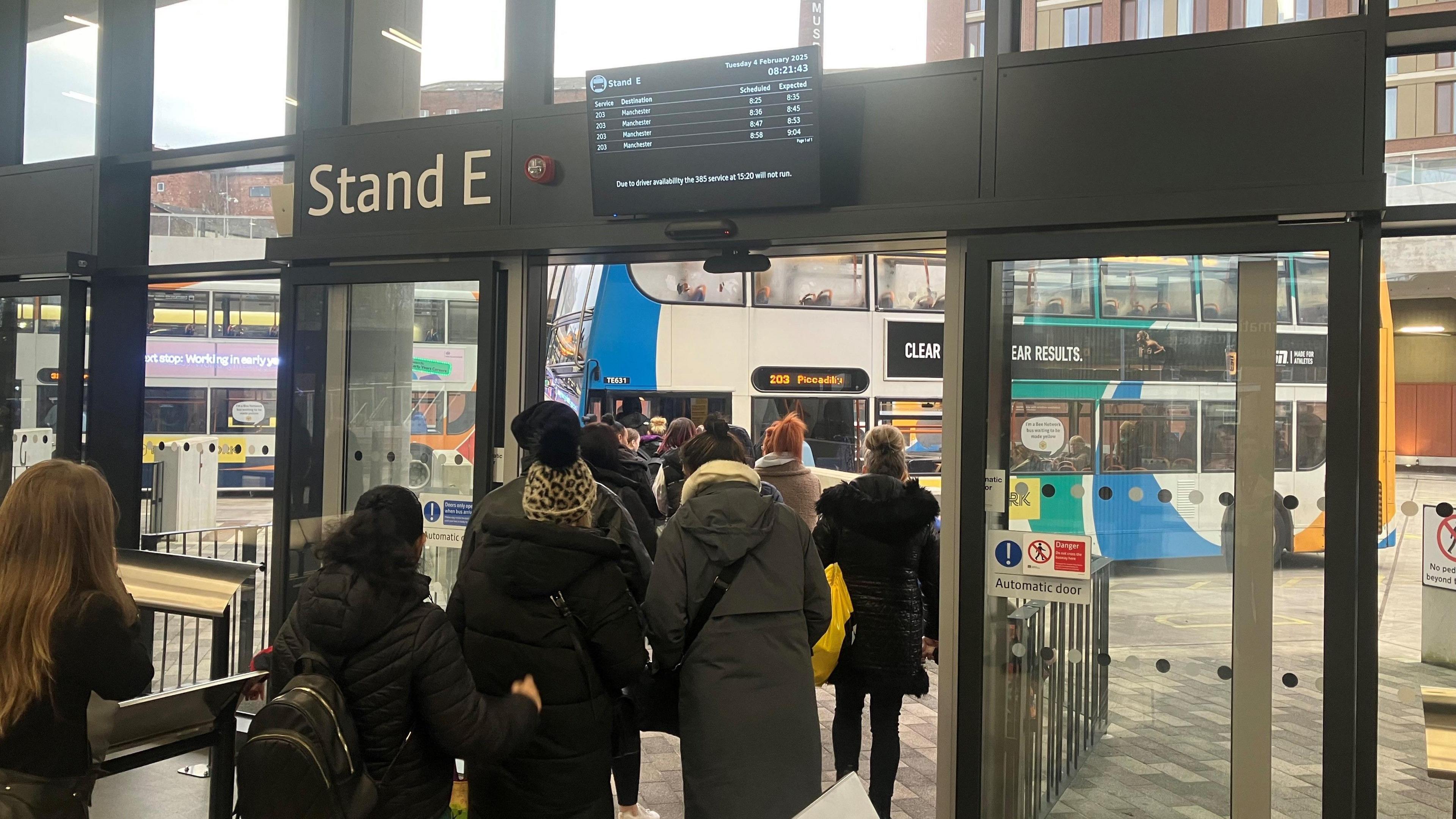 A photograph of passengers boarding the 203 bus service at Stockport Interchange.