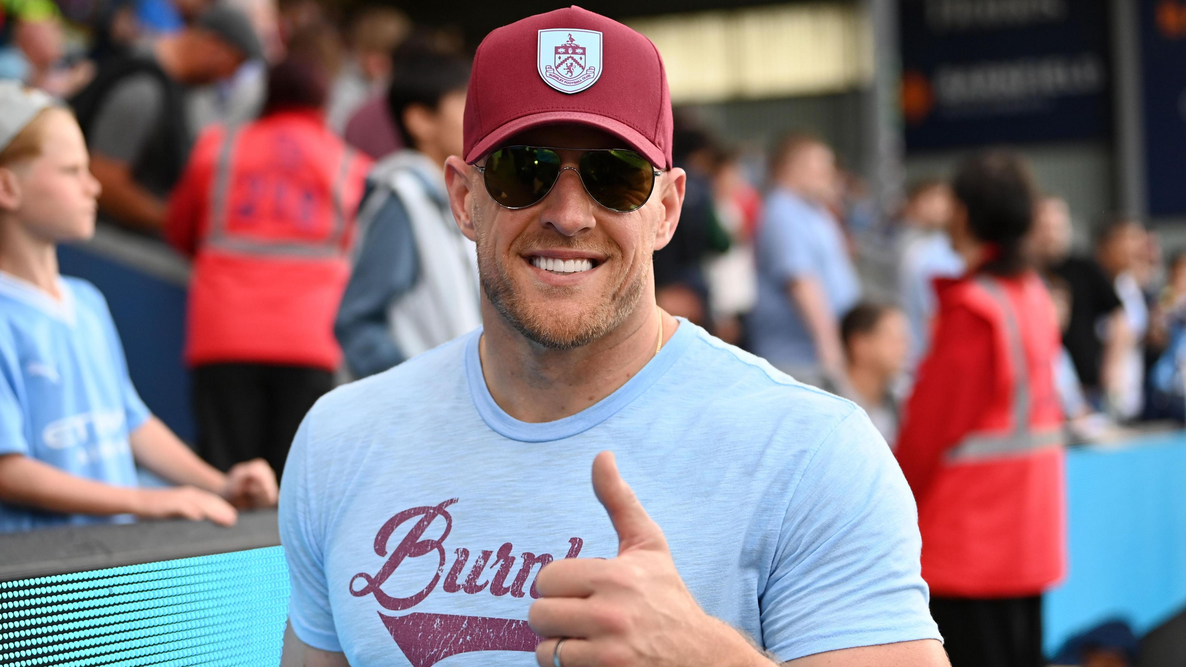 Burnley investor and former NFL star JJ Watt wearing a Burnley T-shirt and baseball cap