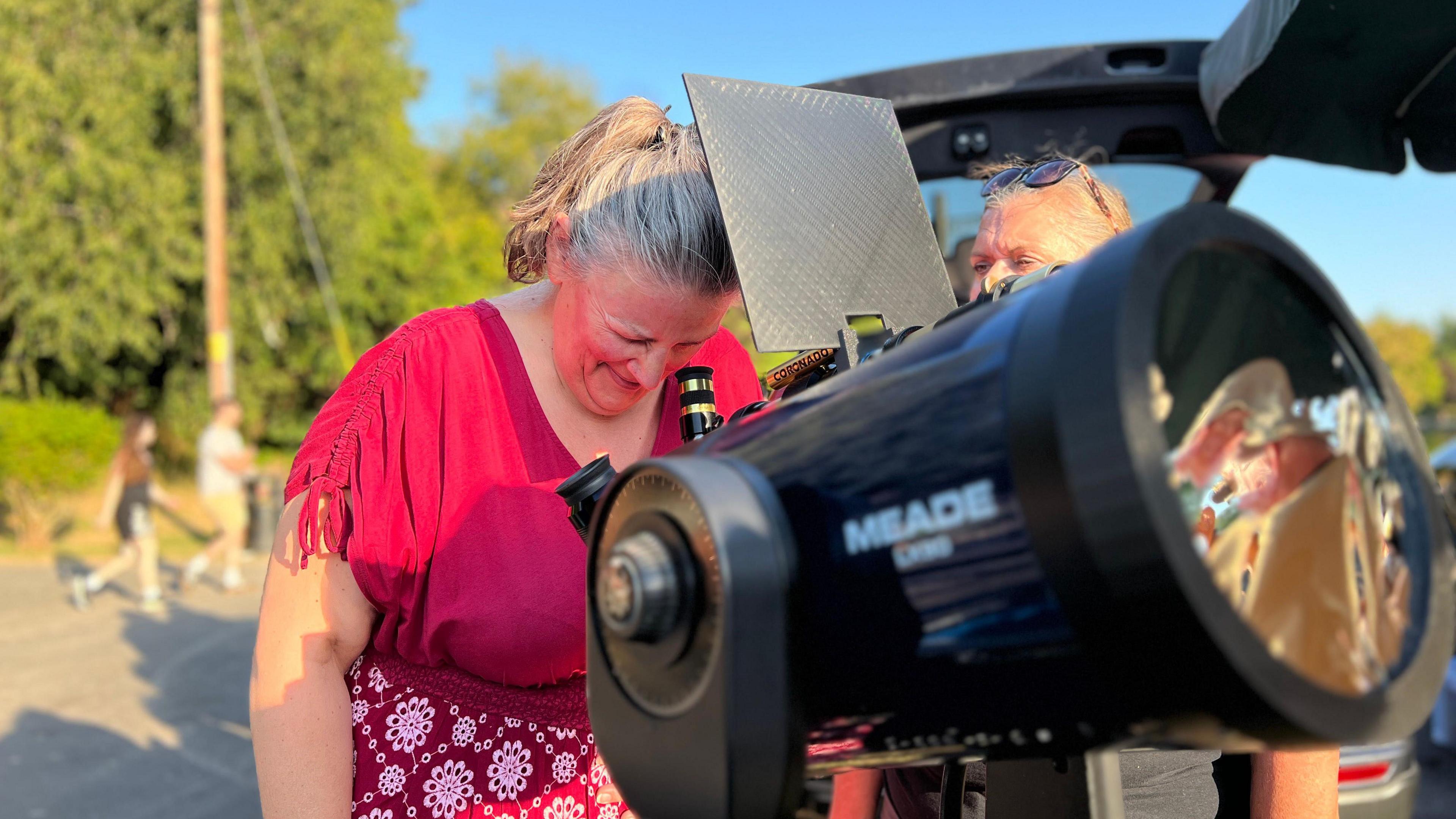 A woman is looking into a large telescope