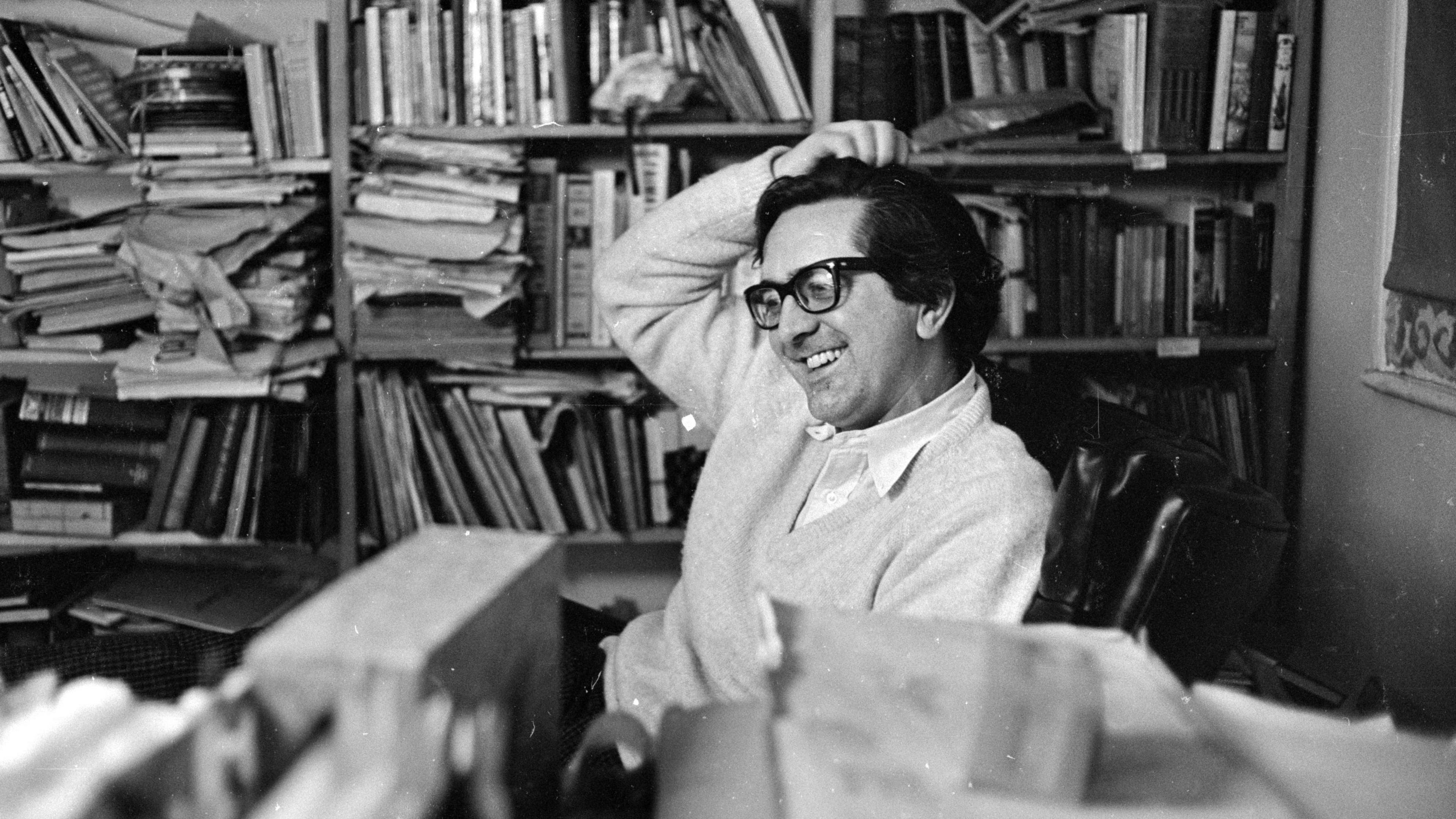 Len Deighton is seen in his office surrounded by books and papers in a black and white photo from 1966