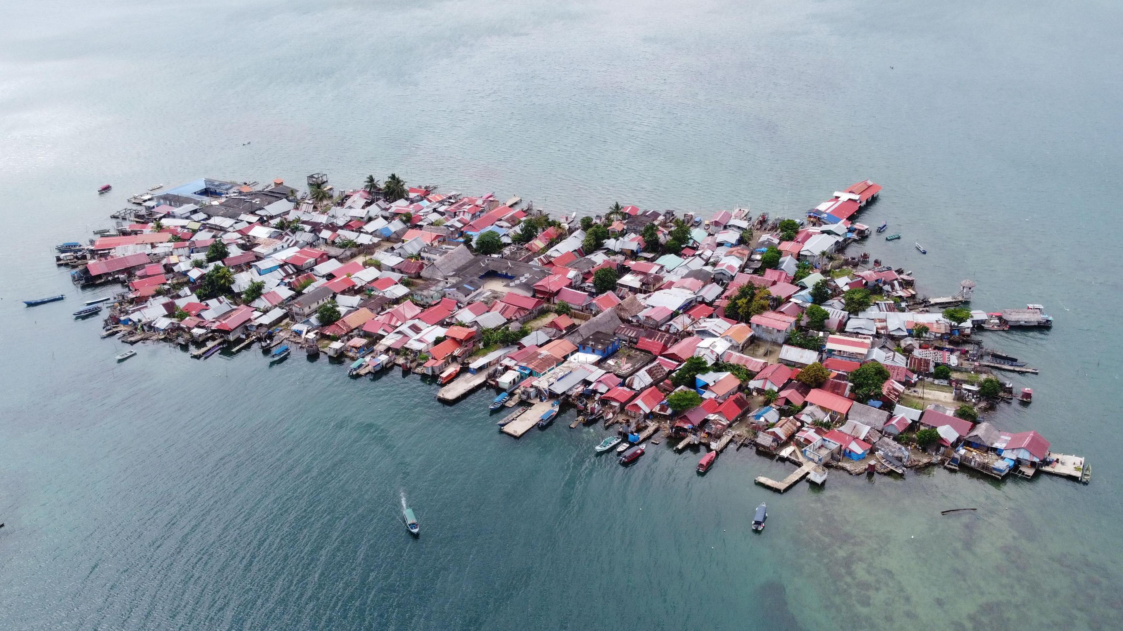 Aerial photo showing the island of Gardi Sugdub, a cluster of densely-packed red and grey roofs with boats, jetties and buildings sticking out into the surrounding ocean in all directions