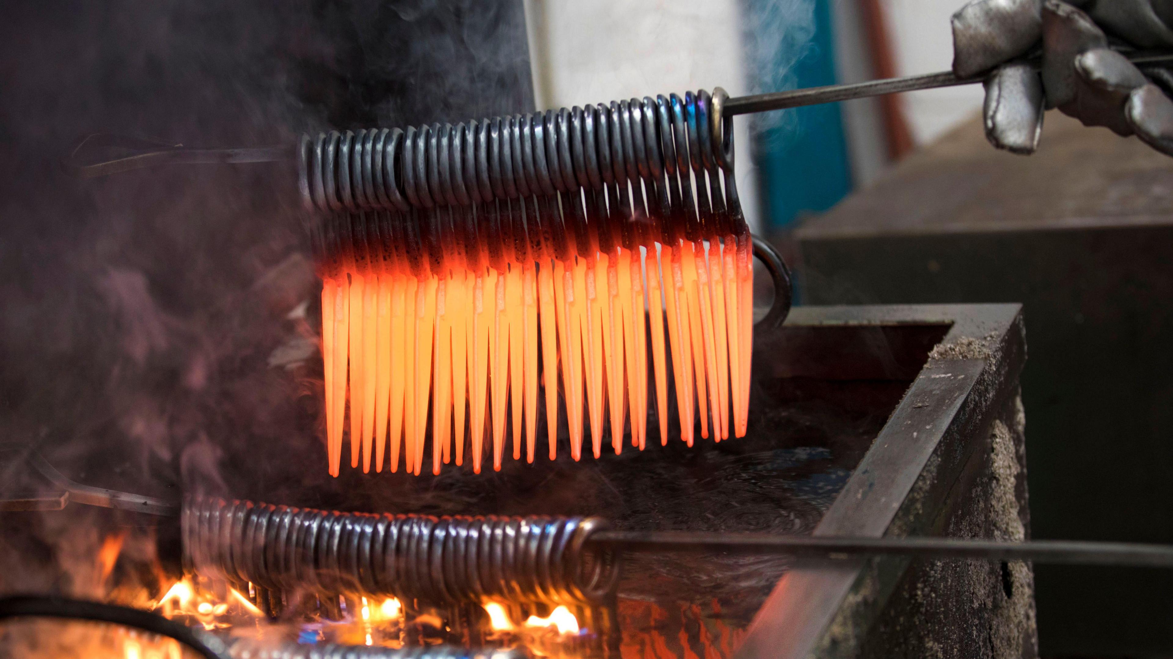 Dozens of red-hot scissors are removed from a forge.