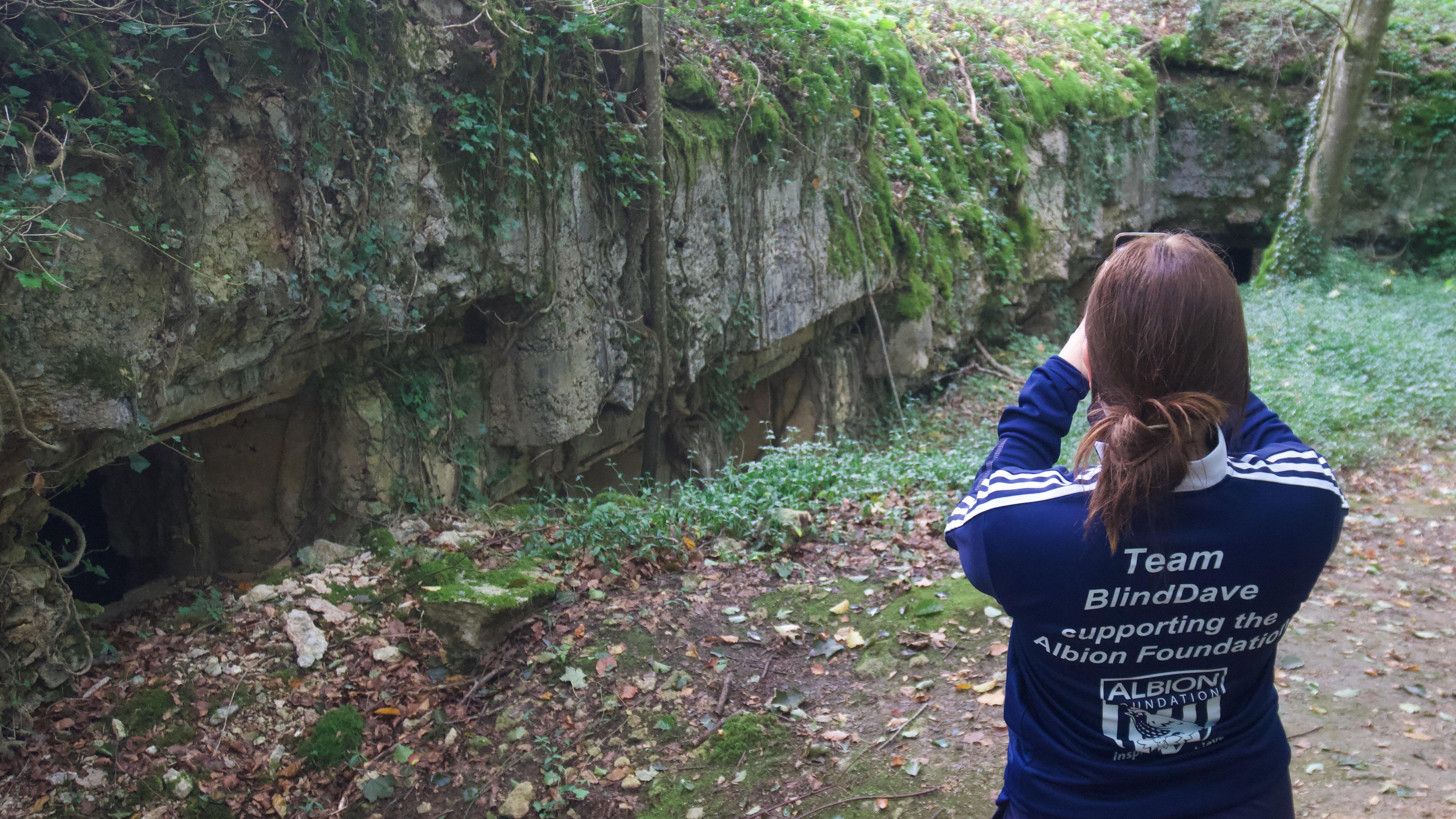 Woman taking photograph of a trench hospital in woodland