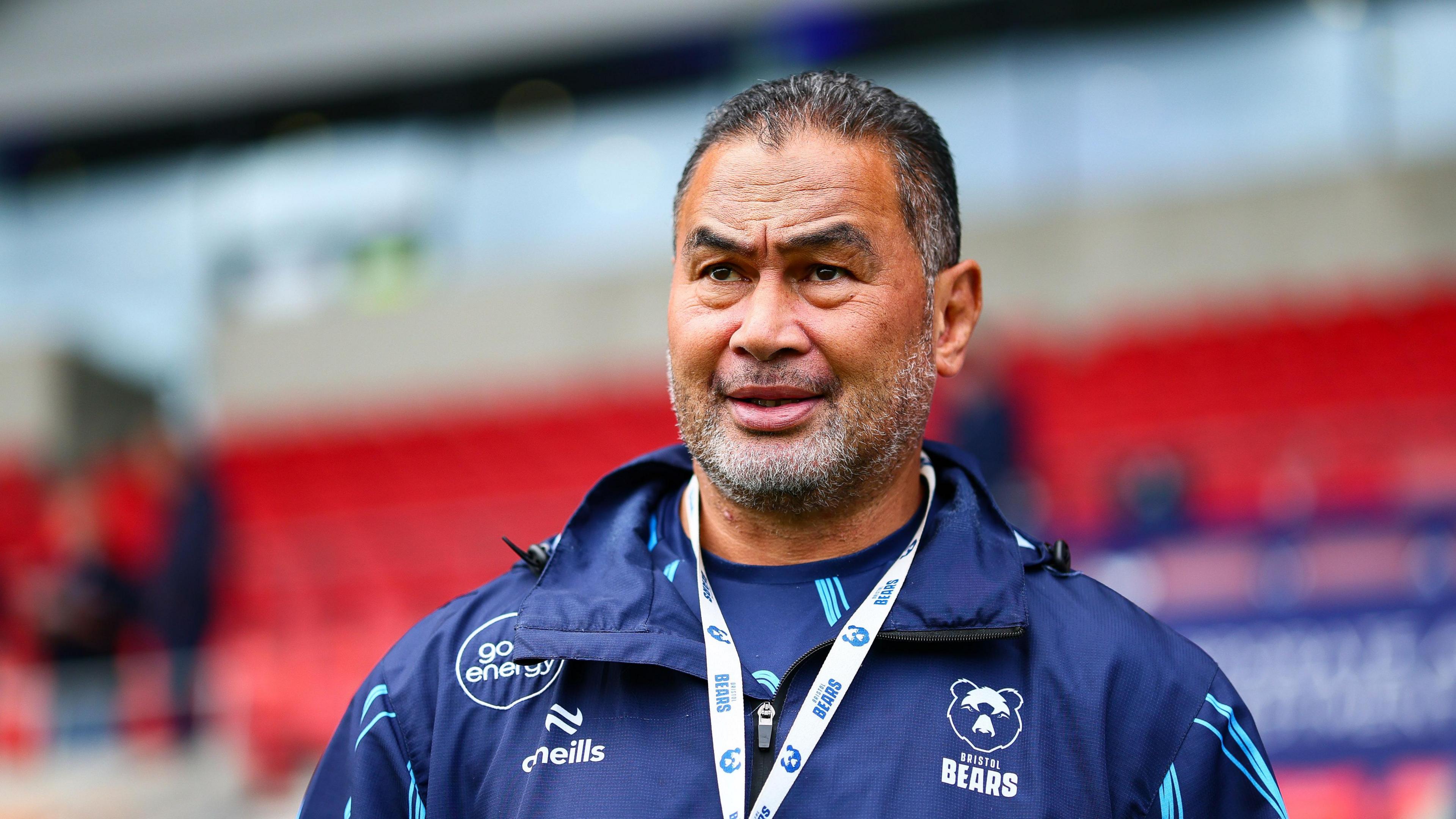 Pat Lam wearing a navy blue Bristol Bears jacket with a Bristol Bears lanyard around his neck ahead of their game at Sale's CorpAcq Stadium