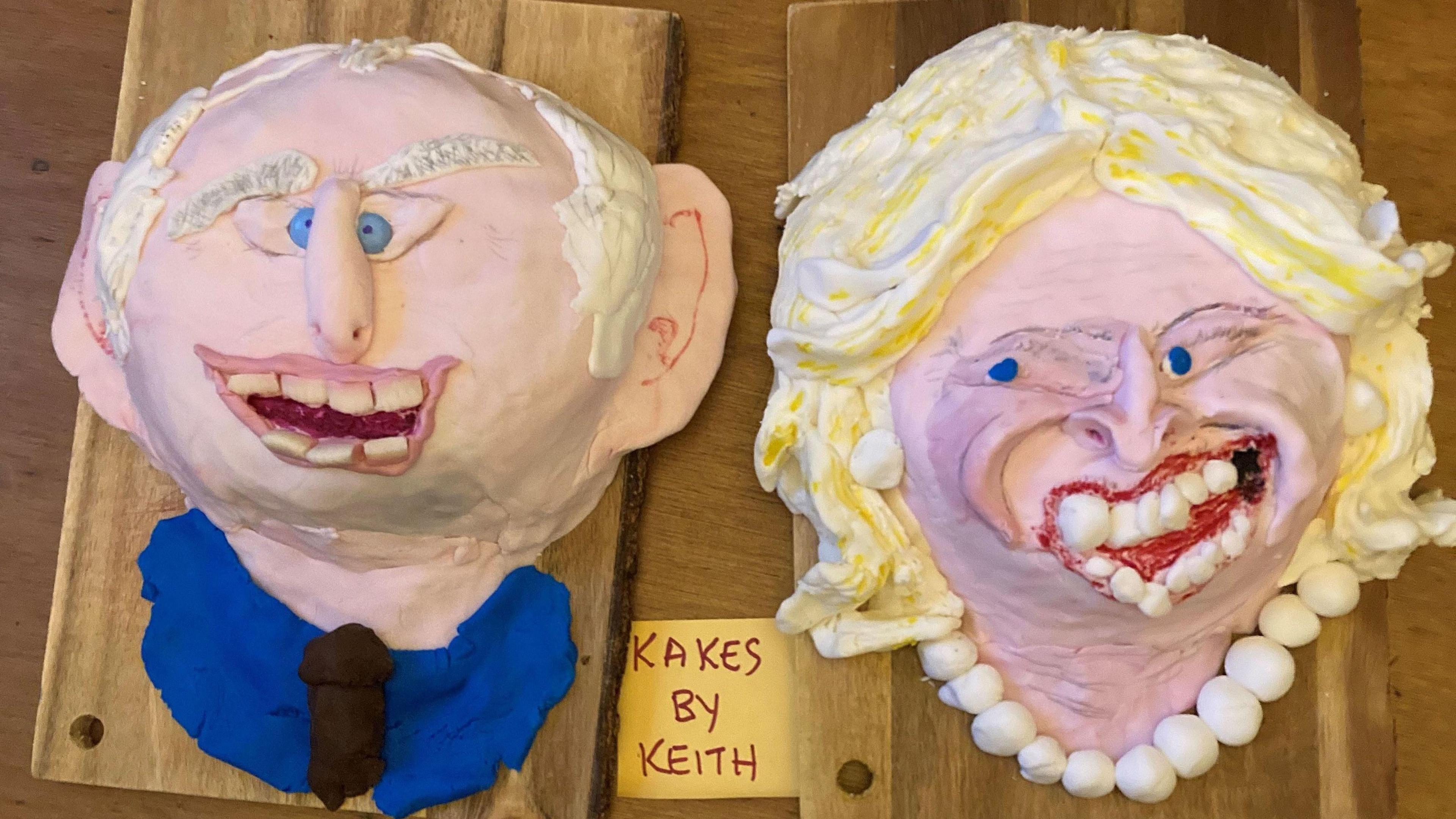 Two caricature cakes, one on the left showing a smiling King Charles, and one showing Queen Camilla with blonde hair and a very broad garish smile